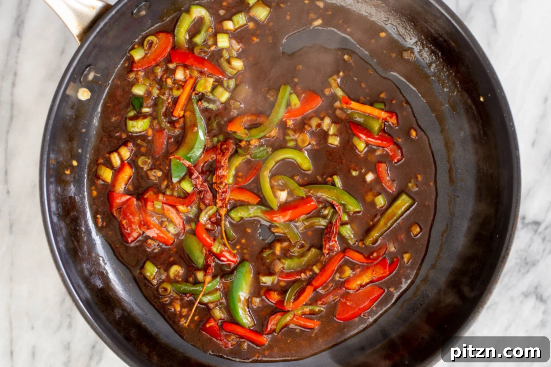 The thickened chili and soy sauce mixture simmering in the frying pan, forming the luscious gravy for the dish.