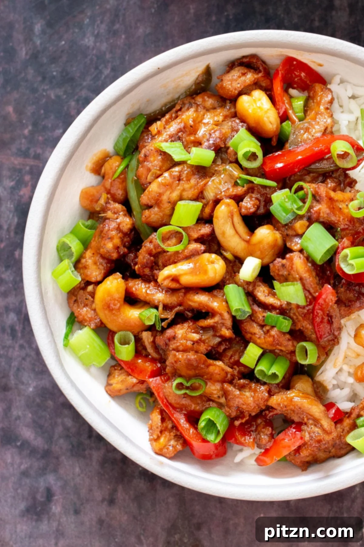 Vegan soycurls, mixed with colorful bell peppers and crunchy cashews, served elegantly over a bed of white rice, ready to be enjoyed.