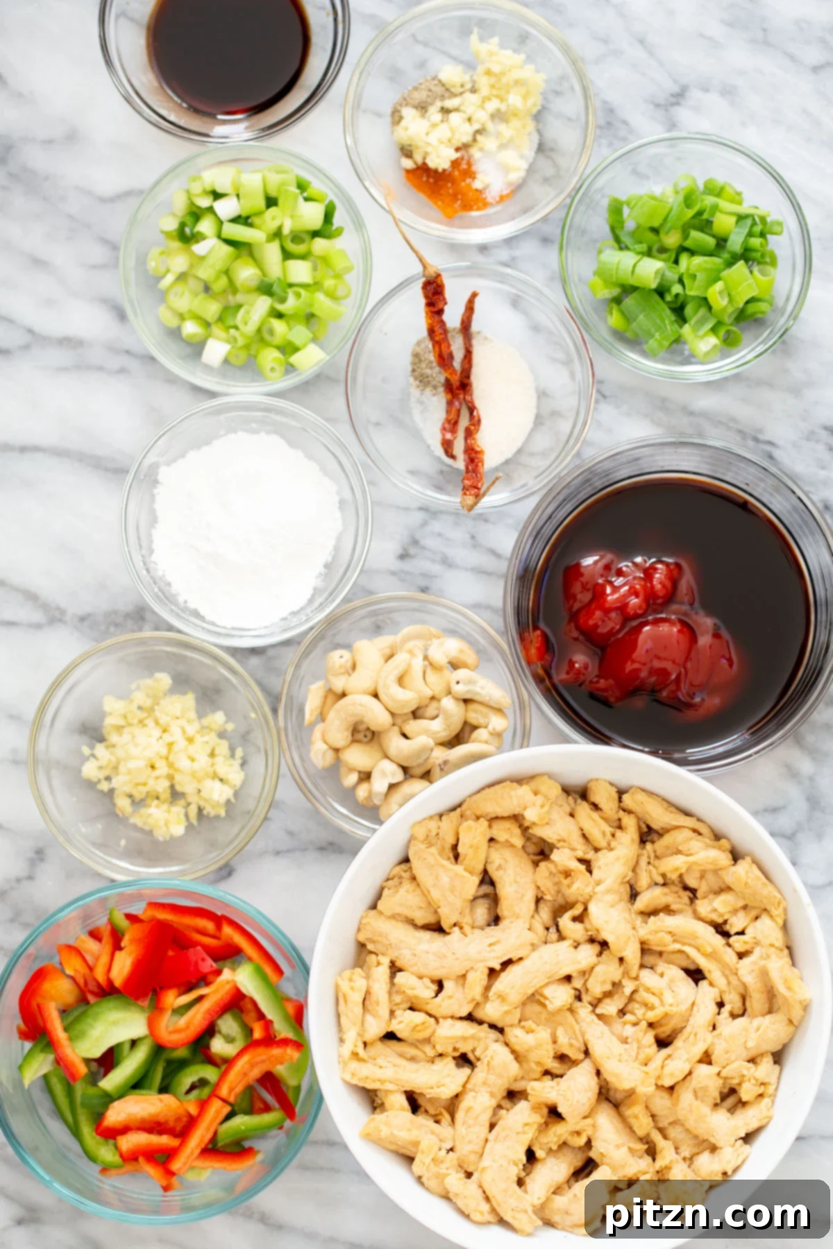 A collection of fresh ingredients laid out for making vegan Dragon Chicken Soycurls, including bell peppers, cashews, sauces, and spices.