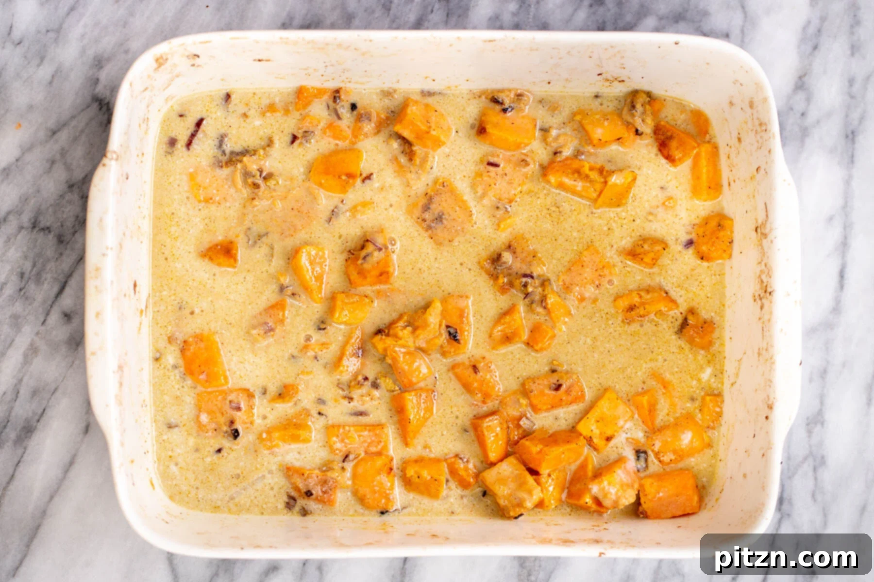 Sweet Potato and Chickpea Curry Bake 10 A casserole dish showing sweet potatoes and other ingredients simmering gently in a vibrant, creamy coconut milk gravy during the second baking stage