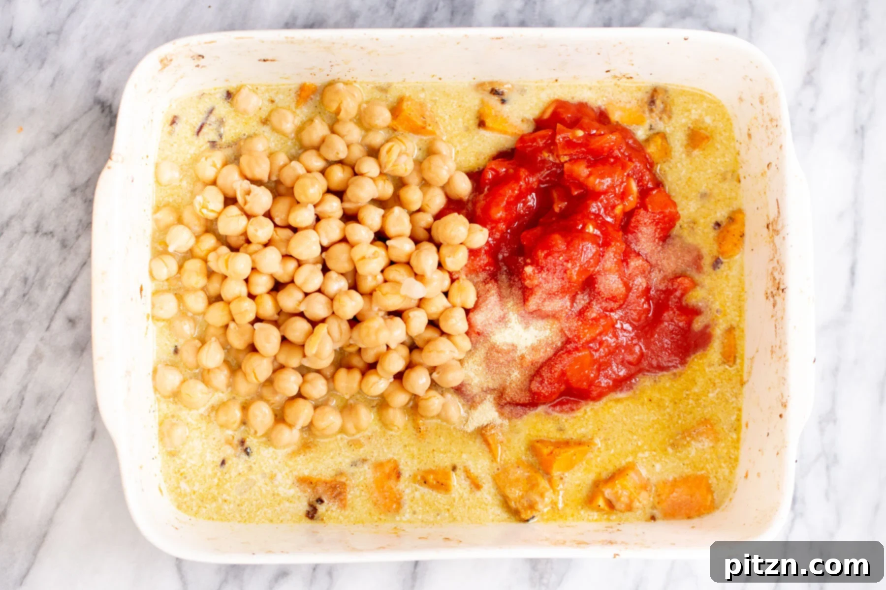 Sweet Potato and Chickpea Curry Bake 11 Adding diced tomatoes and plump canned chickpeas to the baking sweet potato curry in a casserole dish, mixing them into the creamy sauce