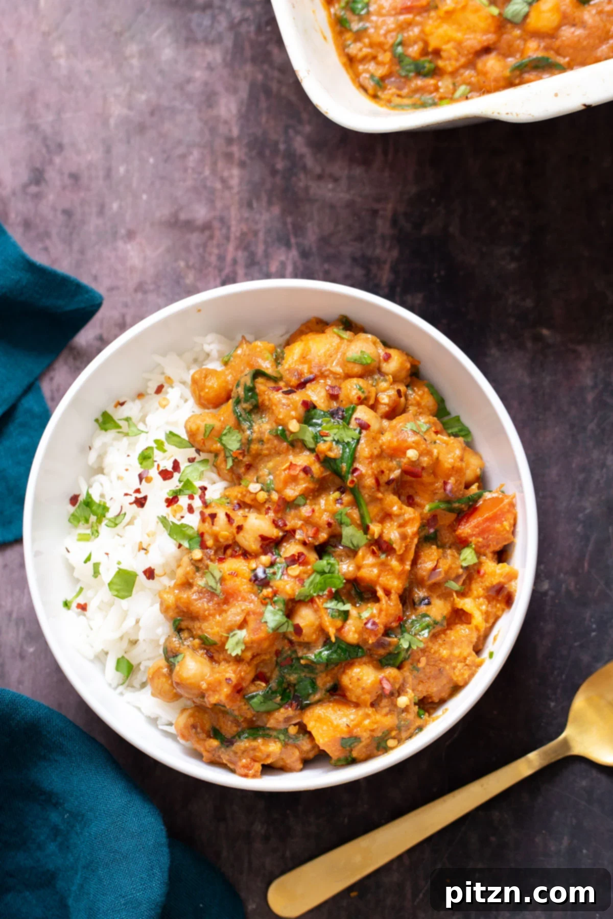 Sweet Potato and Chickpea Curry Bake 5 A bowl of baked chickpea sweet potato curry, served over rice and garnished with fresh cilantro, ready to be enjoyed