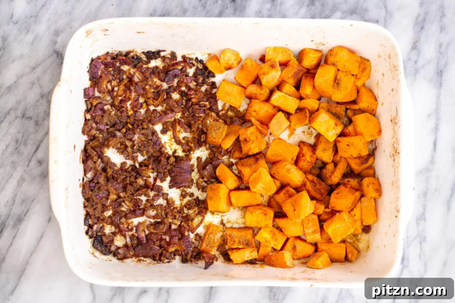 Sweet Potato and Chickpea Curry Bake 8 Golden-brown sweet potato cubes and caramelized onions baking in a casserole dish, richly coated with spices