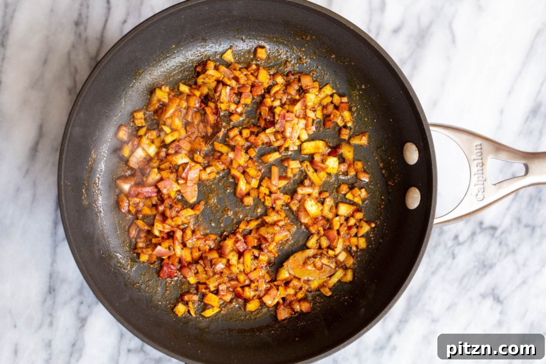 Spicy Black Gram Dal 10 Fried onion cubes with vibrant Indian spices in a black skillet, creating an aromatic base