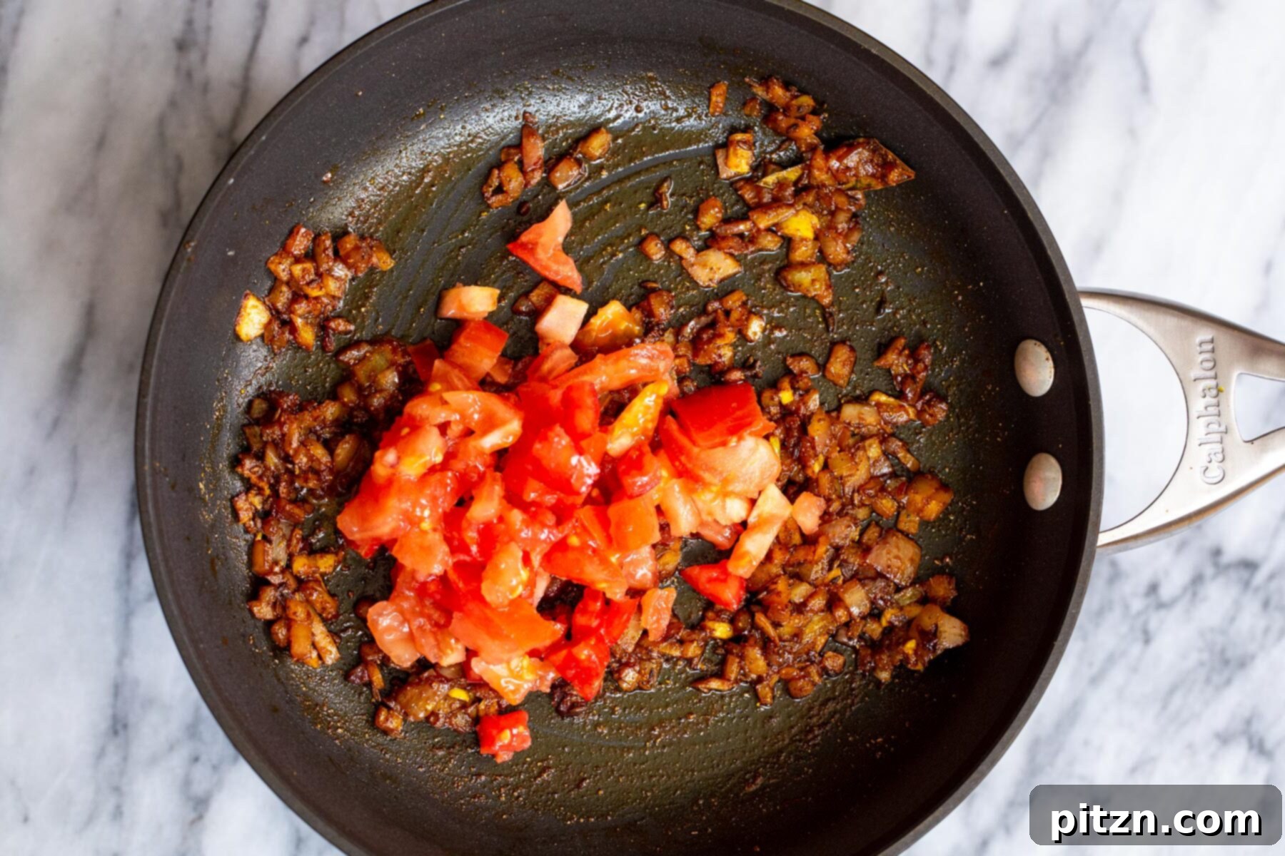 Spicy Black Gram Dal 12 Freshly chopped tomatoes being added to the skillet with onions and spices