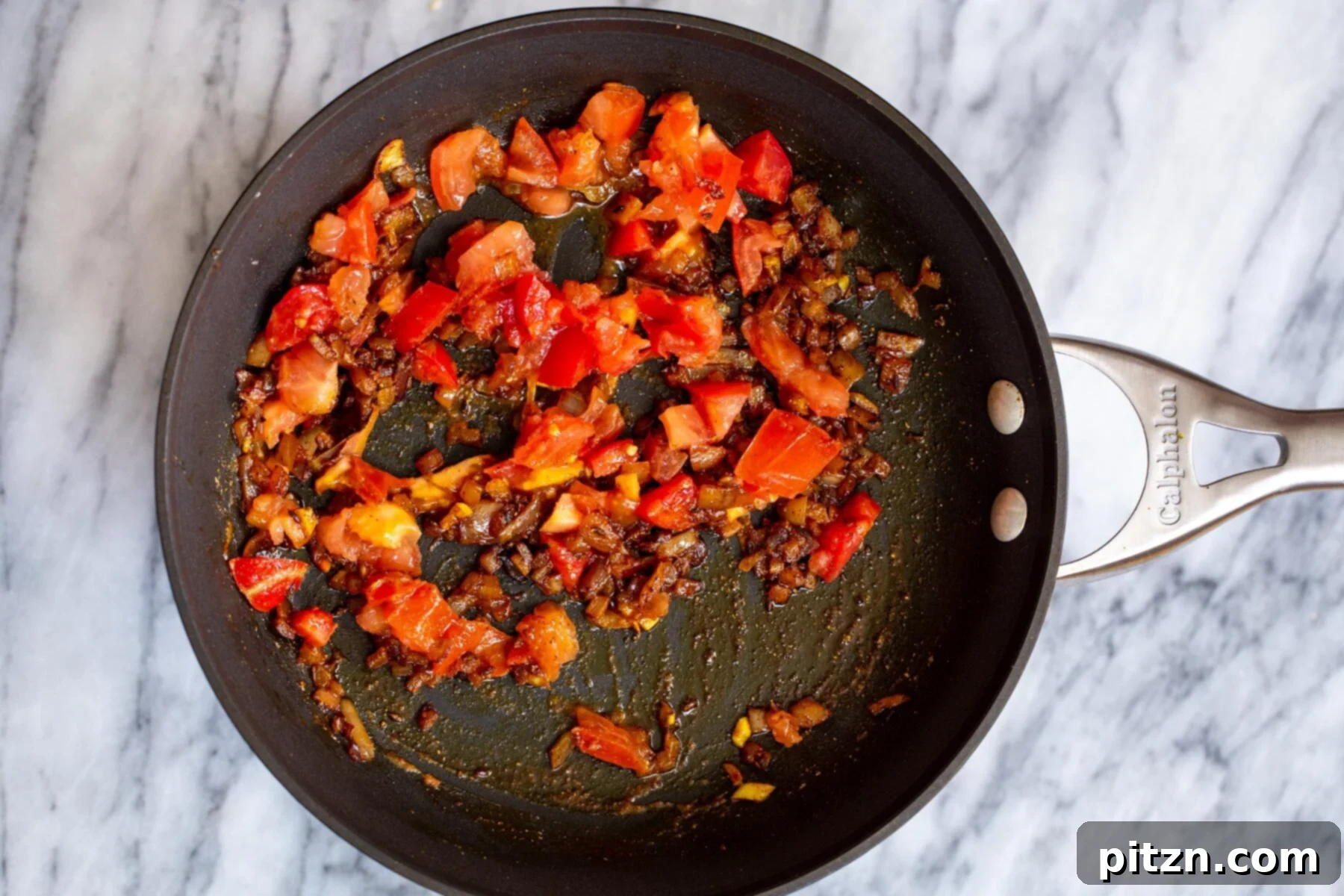 Spicy Black Gram Dal 13 Sautéed tomatoes, onions, and spices simmering in a black skillet, forming a rich base