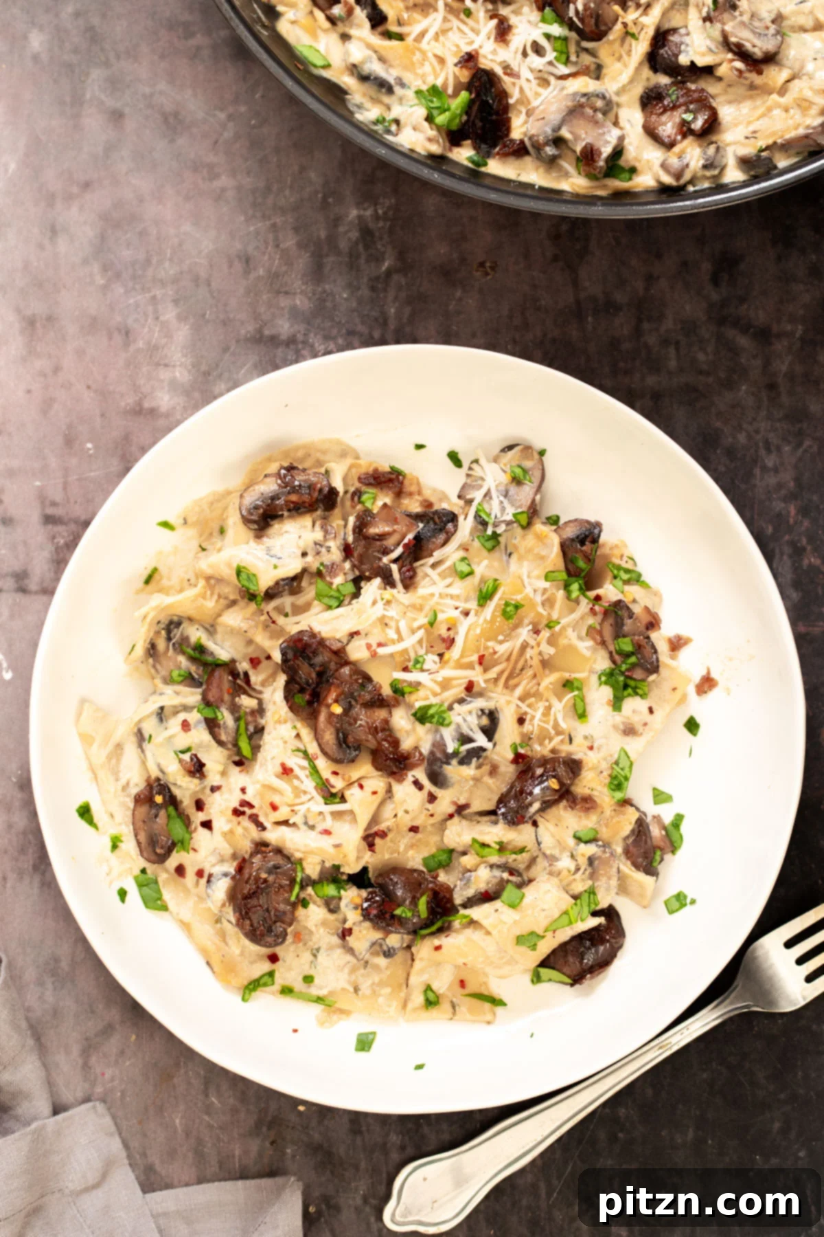 Effortless One-Pan Vegan White Lasagna with Tofu Bechamel 2 a plate with vegan skillet lasagna topped with balsamic mushrooms and vegan parmesan cheese