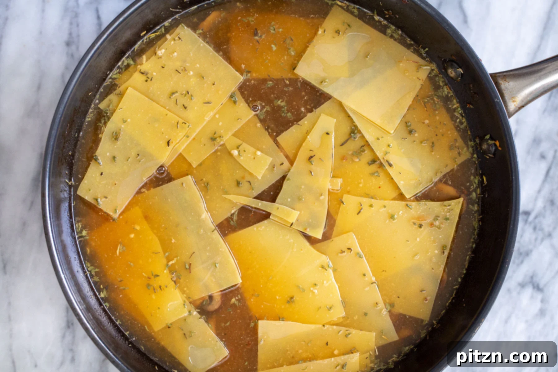 Effortless One-Pan Vegan White Lasagna with Tofu Bechamel 15 broken pasta noodles cooking in a black skillet