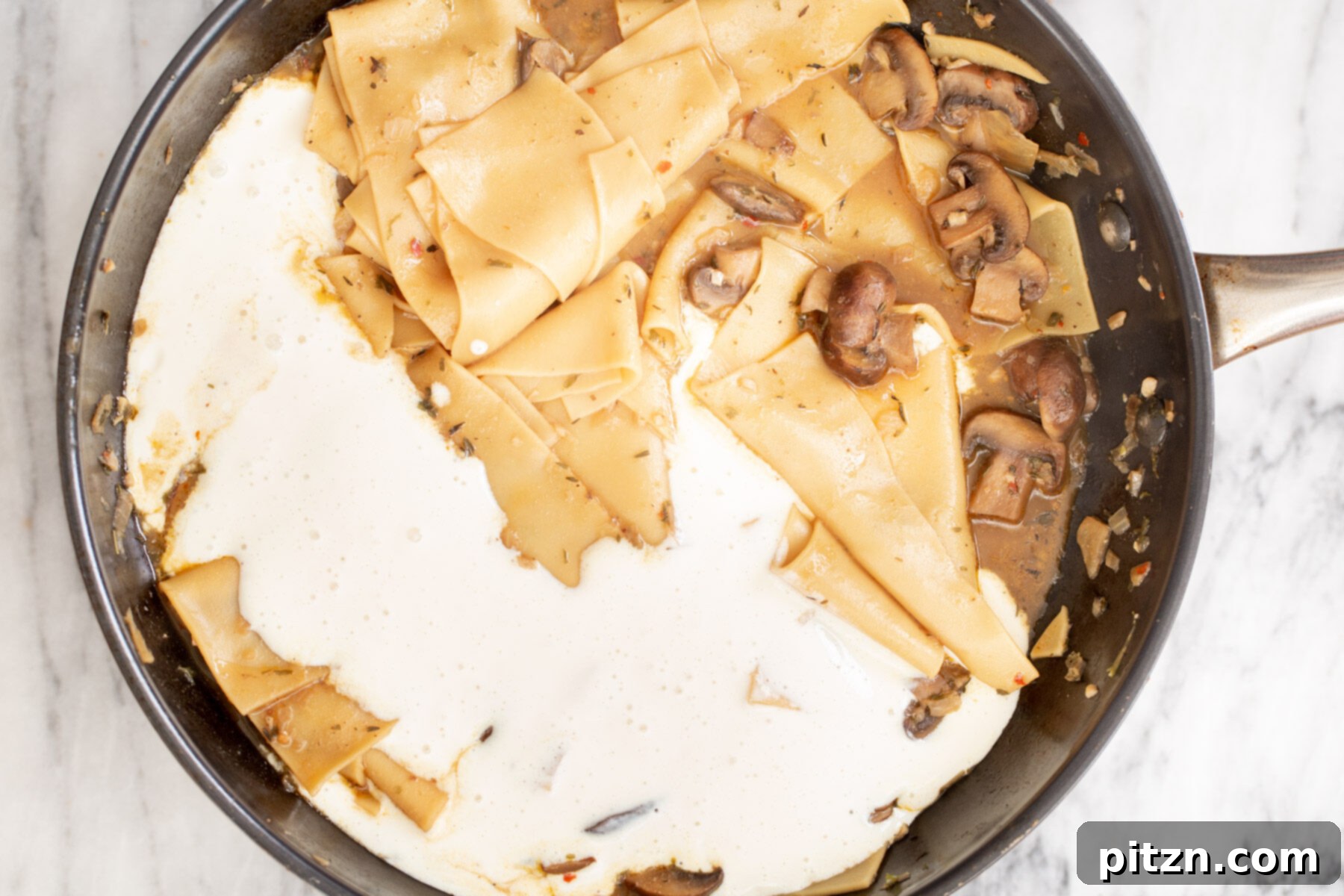 Effortless One-Pan Vegan White Lasagna with Tofu Bechamel 17 dairyfree vegan tofu bechamel being added to skillet with mushroom pasta