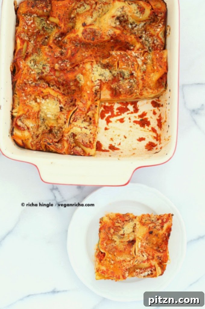 A top-down view of the baked Vegan Cauliflower Alfredo Spinach Artichoke Lasagna, with steam gently rising, highlighting its readiness to be enjoyed. The rich textures and colors are inviting.