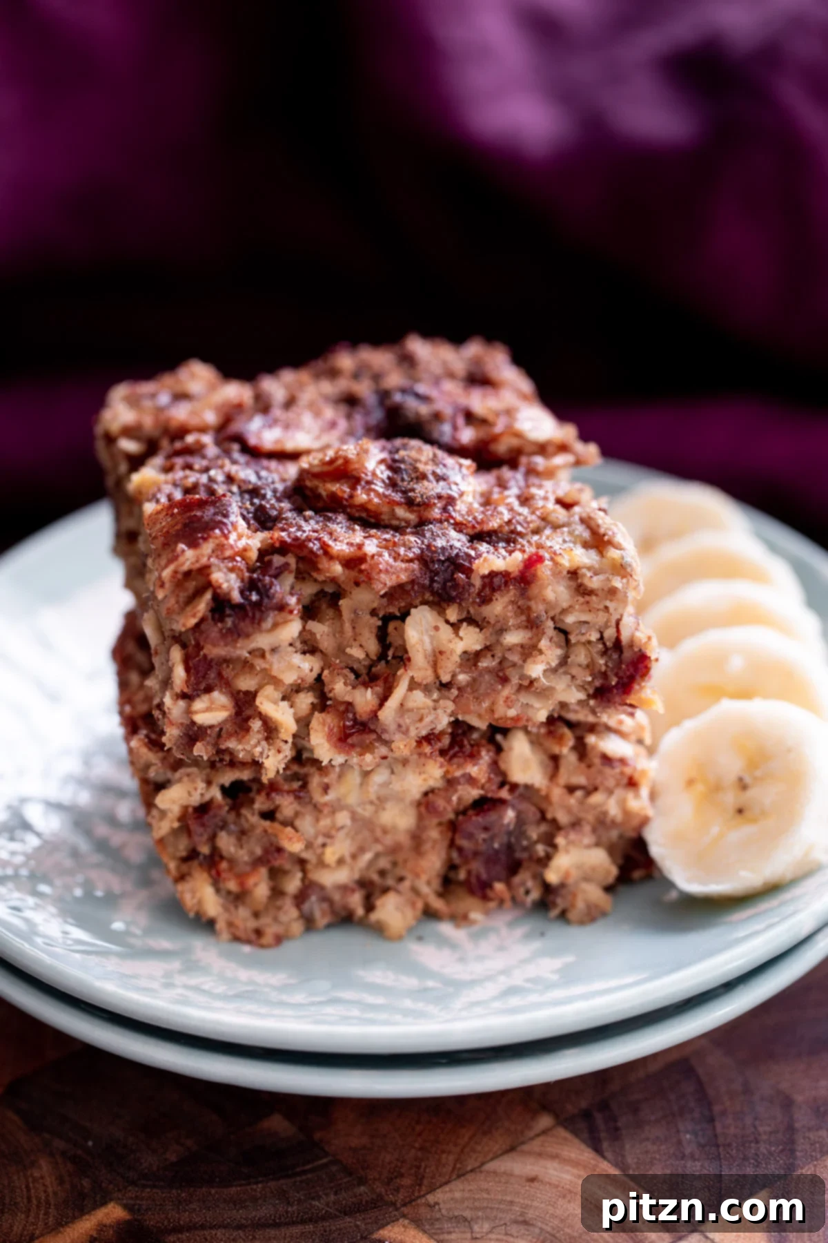 Delicious Vegan Banana Oatmeal Bars with Caramelized Topping Stacked vegan banana oatmeal bars on a white plate, showcasing the caramelized banana and cinnamon crumb topping.