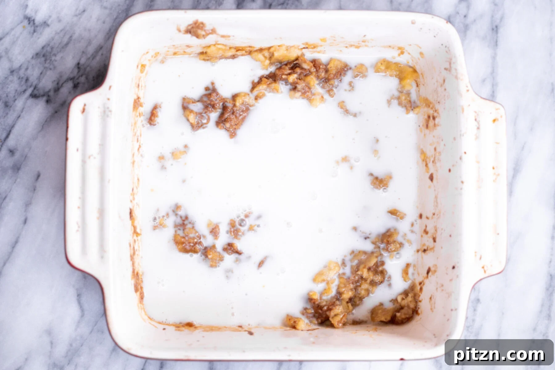 Cinnamon Streusel Vegan Banana Oat Squares 10 Non-dairy milk being poured into the banana and almond butter mixture in a casserole dish, to create a smooth batter.