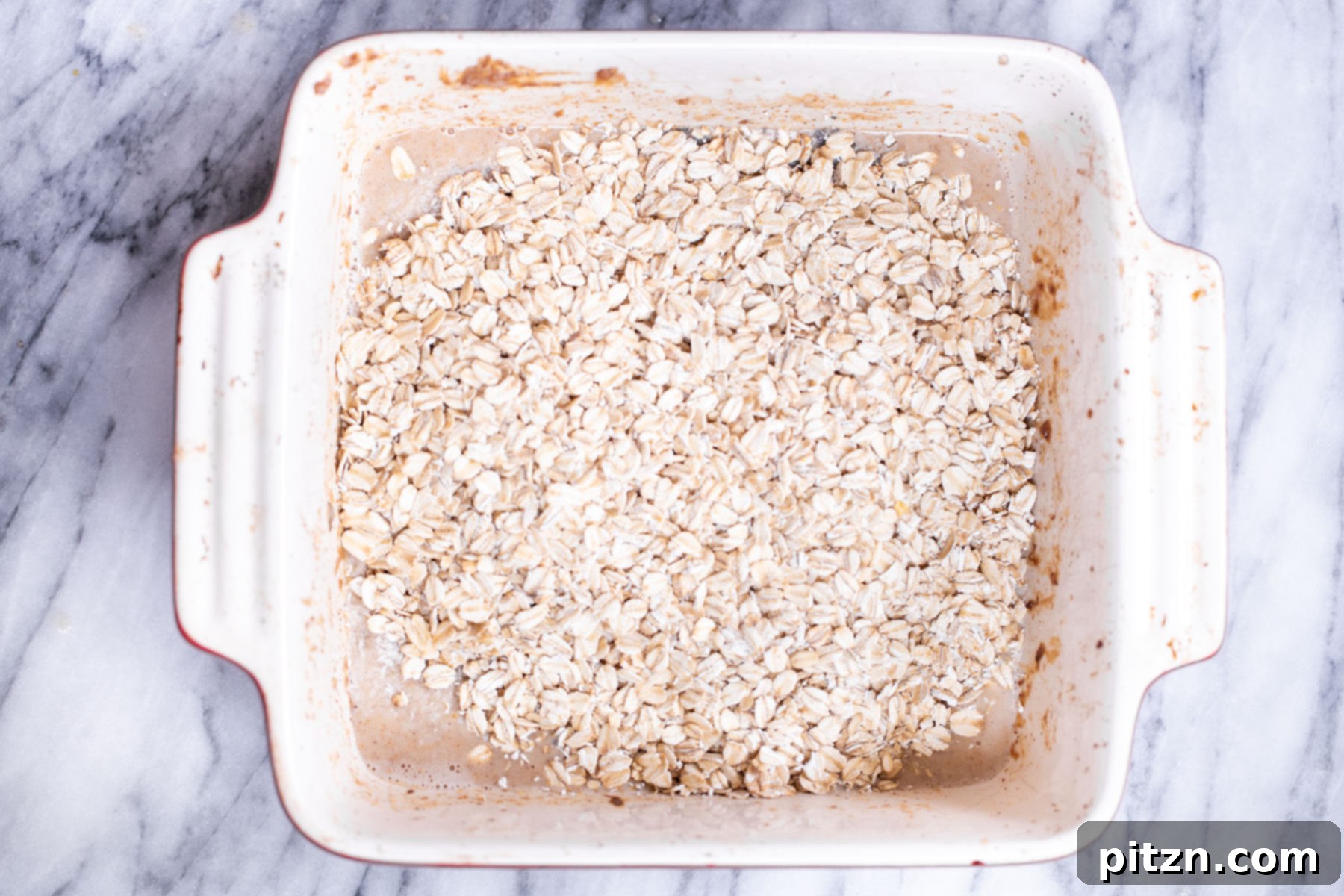 Cinnamon Streusel Vegan Banana Oat Squares 13 Hearty rolled oats being gently folded into the banana batter, forming the wholesome base of the oatmeal bars.