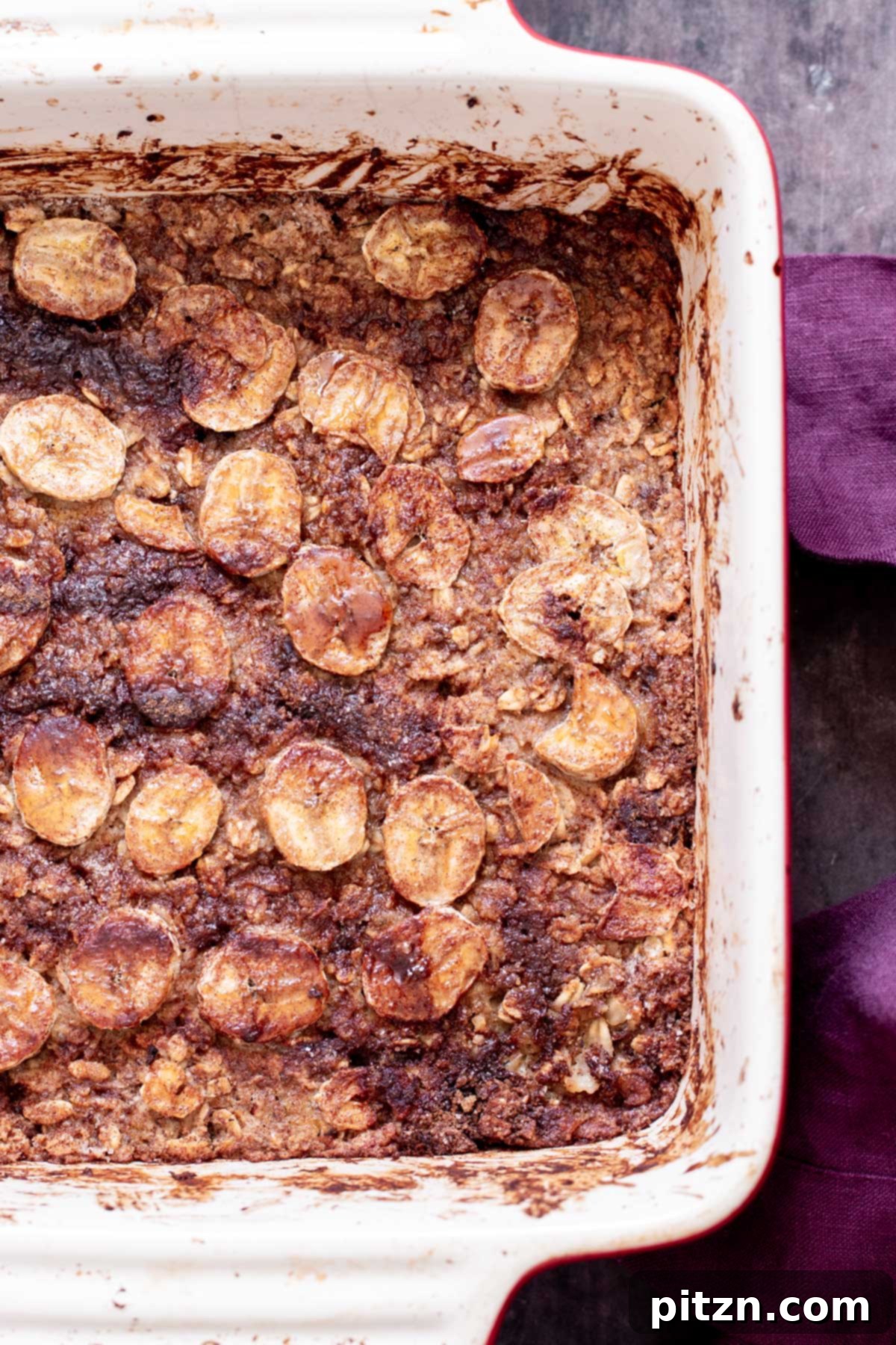 Cinnamon Streusel Vegan Banana Oat Squares 2 A casserole dish filled with freshly baked vegan banana oatmeal bars, adorned with perfectly sliced caramelized bananas on top.