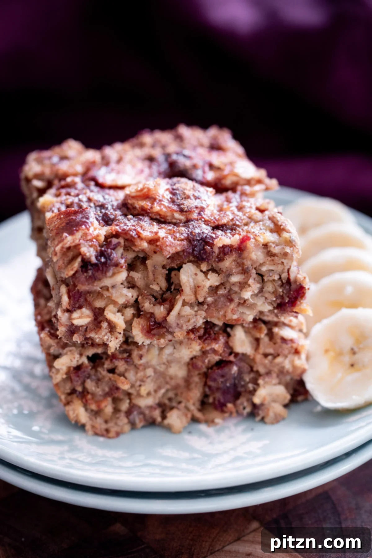 Cinnamon Streusel Vegan Banana Oat Squares 3 Banana Oatmeal Bars stacked with a side of sliced bananas, highlighting the moist texture and appealing topping.