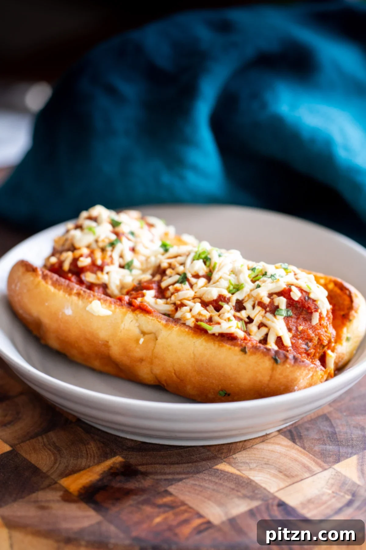 A freshly prepared vegan meatball sub featuring perfectly rounded lentil meatballs, rich tomato sauce, and a generous sprinkle of vegan cheese shreds