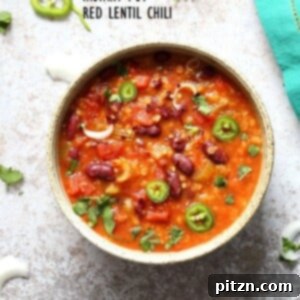 A bowl of instant pot red lentil chili on a white background with a turquoise napkin