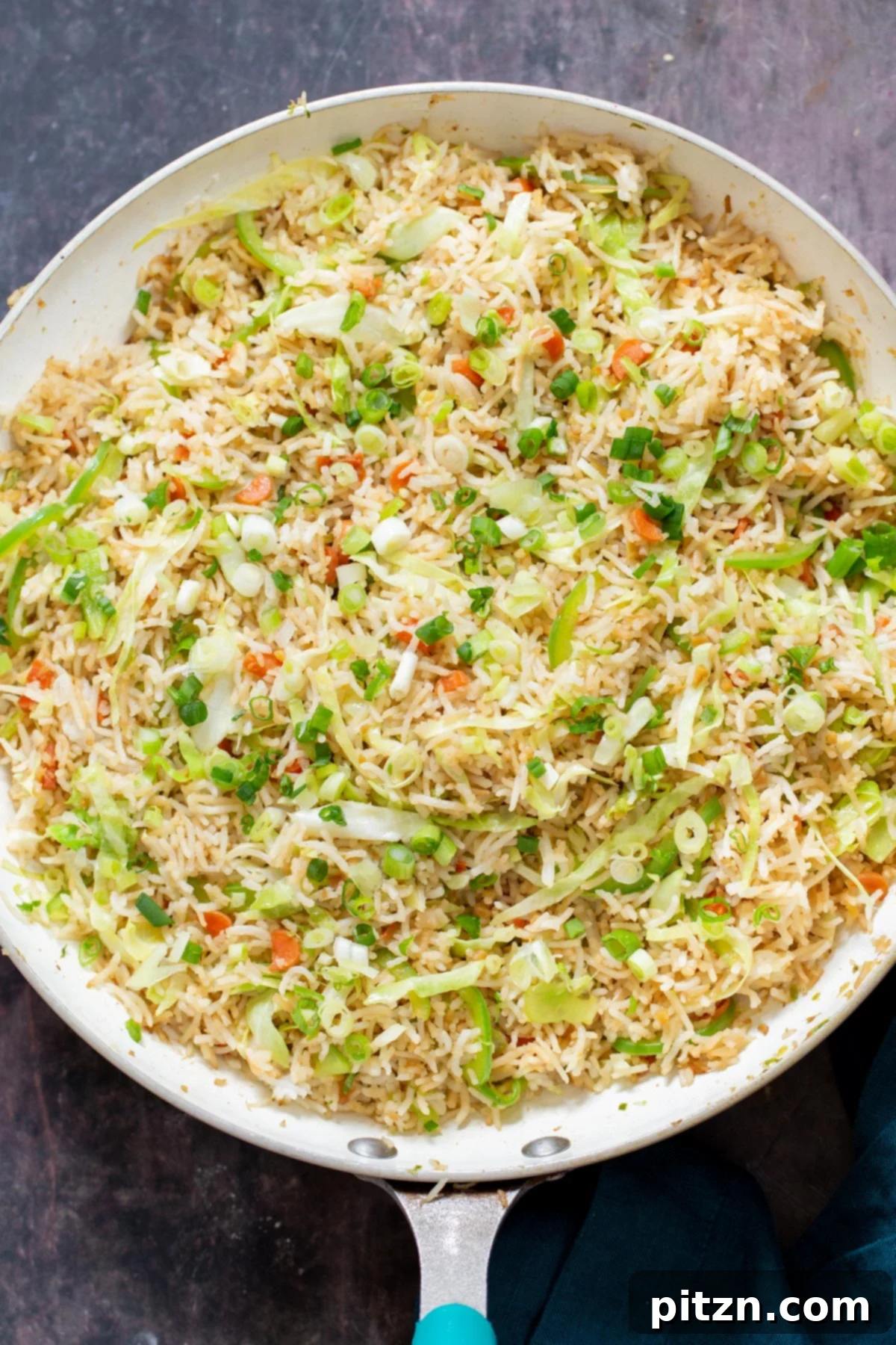 Indo-Chinese Fried Rice 12 A frying pan filled with Indo-Chinese Fried Rice, sprinkled with vibrant scallions, ready to be served as a delicious meal.