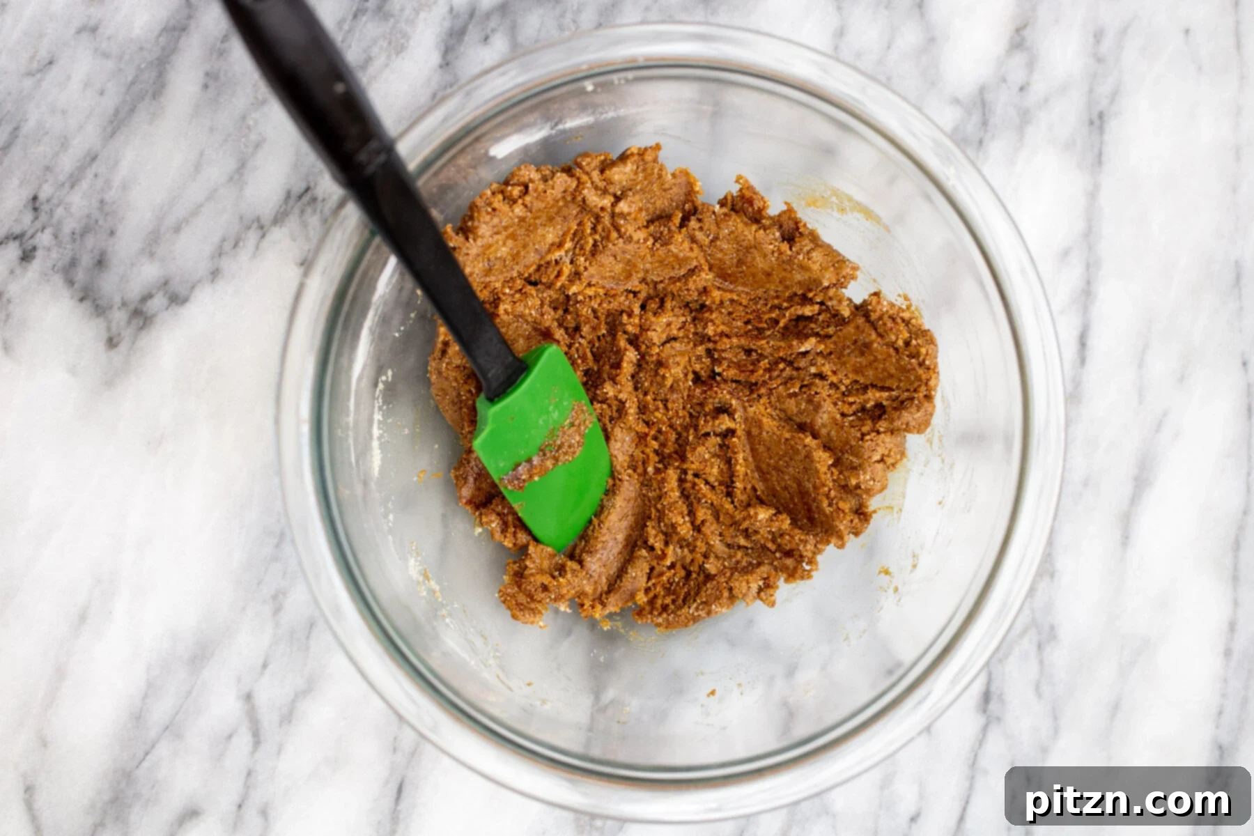 The perfectly mixed ginger almond flour cookie dough rests in a clear glass bowl, ready for chilling and shaping into delectable vegan treats.
