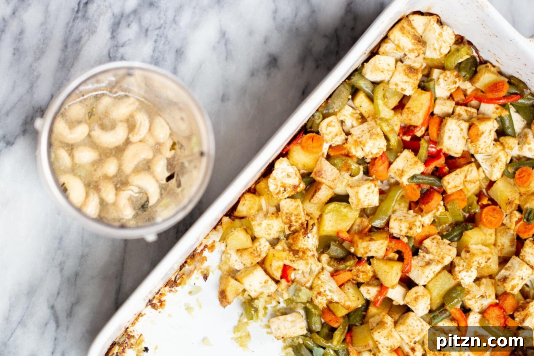 A bowl of soaked cashews next to a sheet pan featuring beautifully toasted tofu and roasted vegetables, prepared for the creamy Korma sauce.