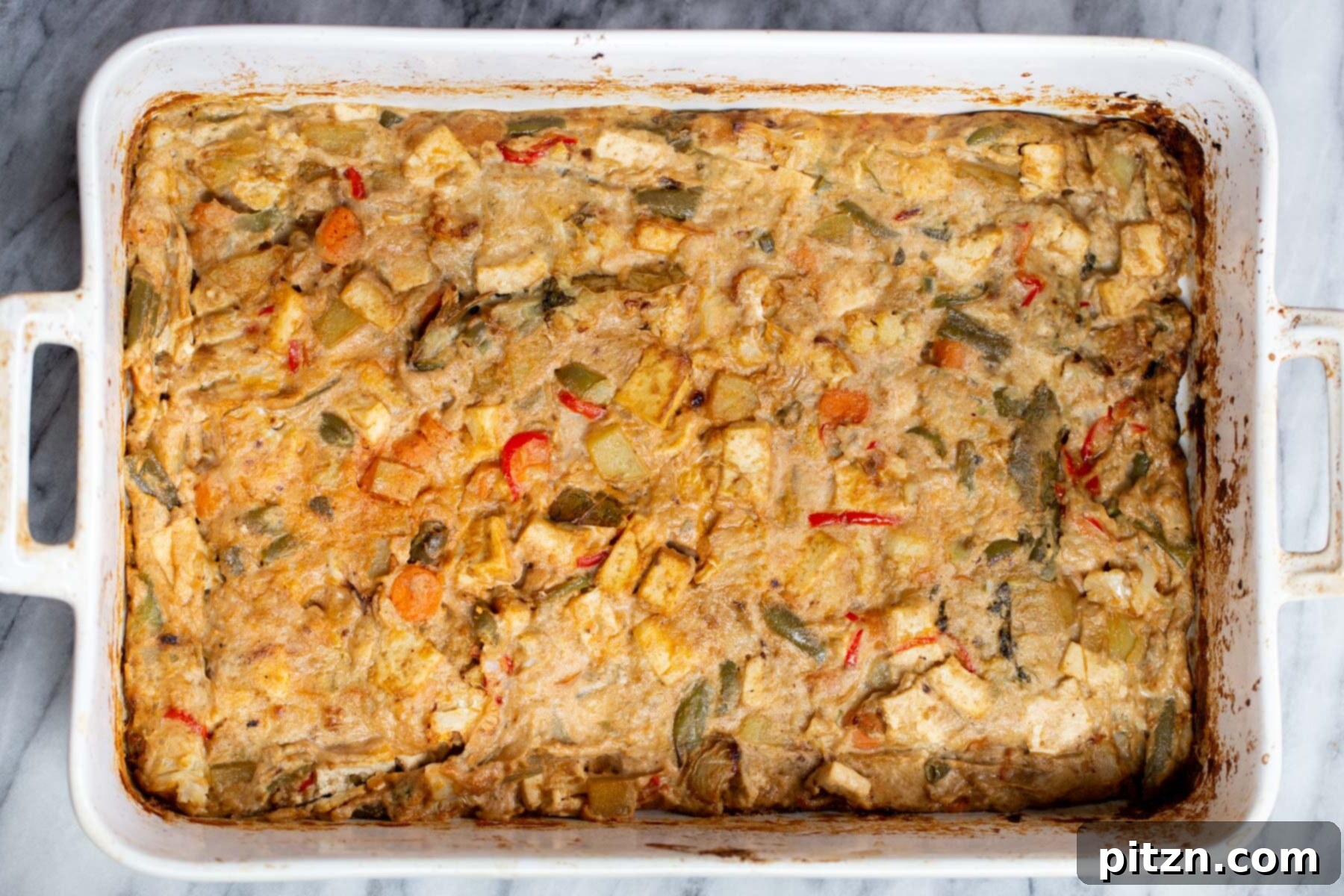 Baked Vegan Navratan Korma in a white casserole dish, garnished and ready to be served, highlighting its luscious texture.