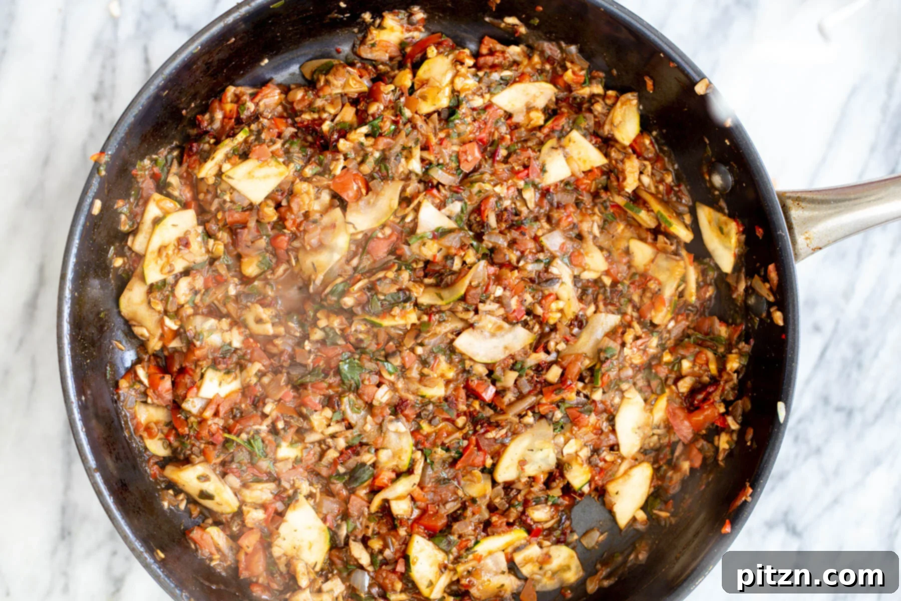 Colorful vegetables stir-frying in a black sautéing pan, a harmonious blend of textures and colors for the pasta.