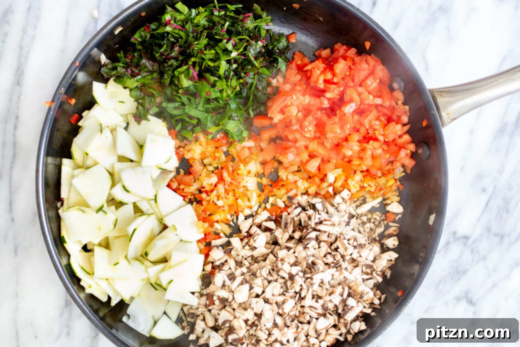 Chopped chard and other vegetables being added to a sautéing pan, building layers of flavor for the pasta.