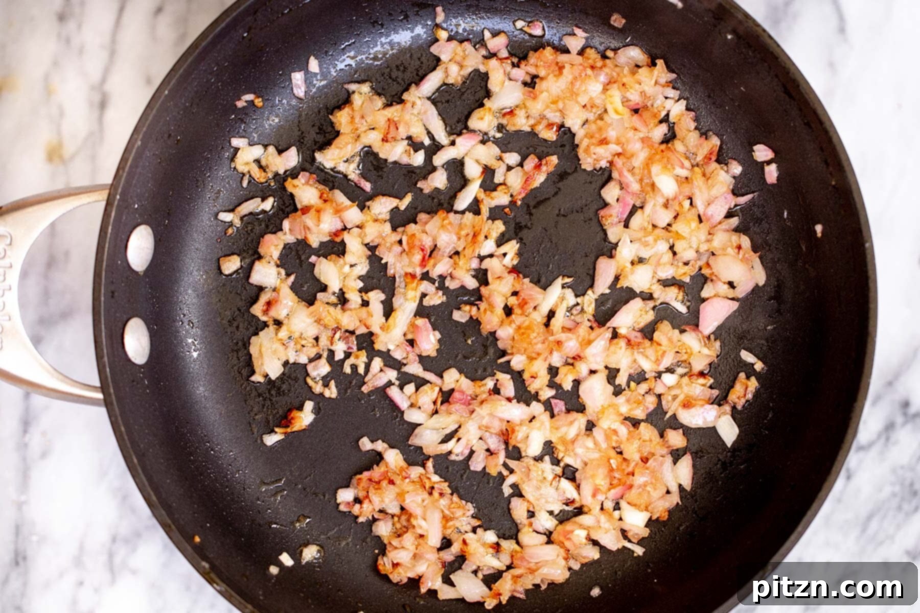 Perfectly fried diced onions, golden and tender, resting in a skillet, ready for the next step of the curry.