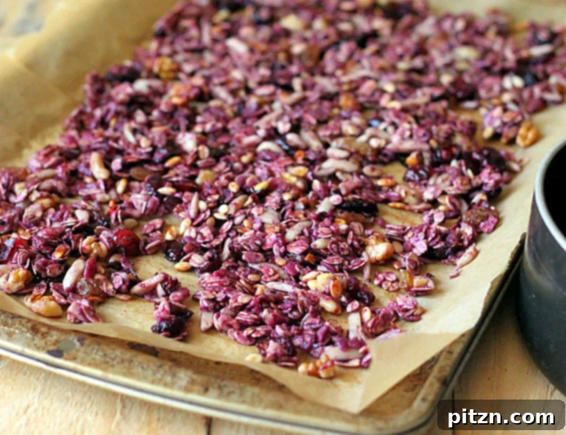 Granola mixture spread on parchment paper, ready for baking.