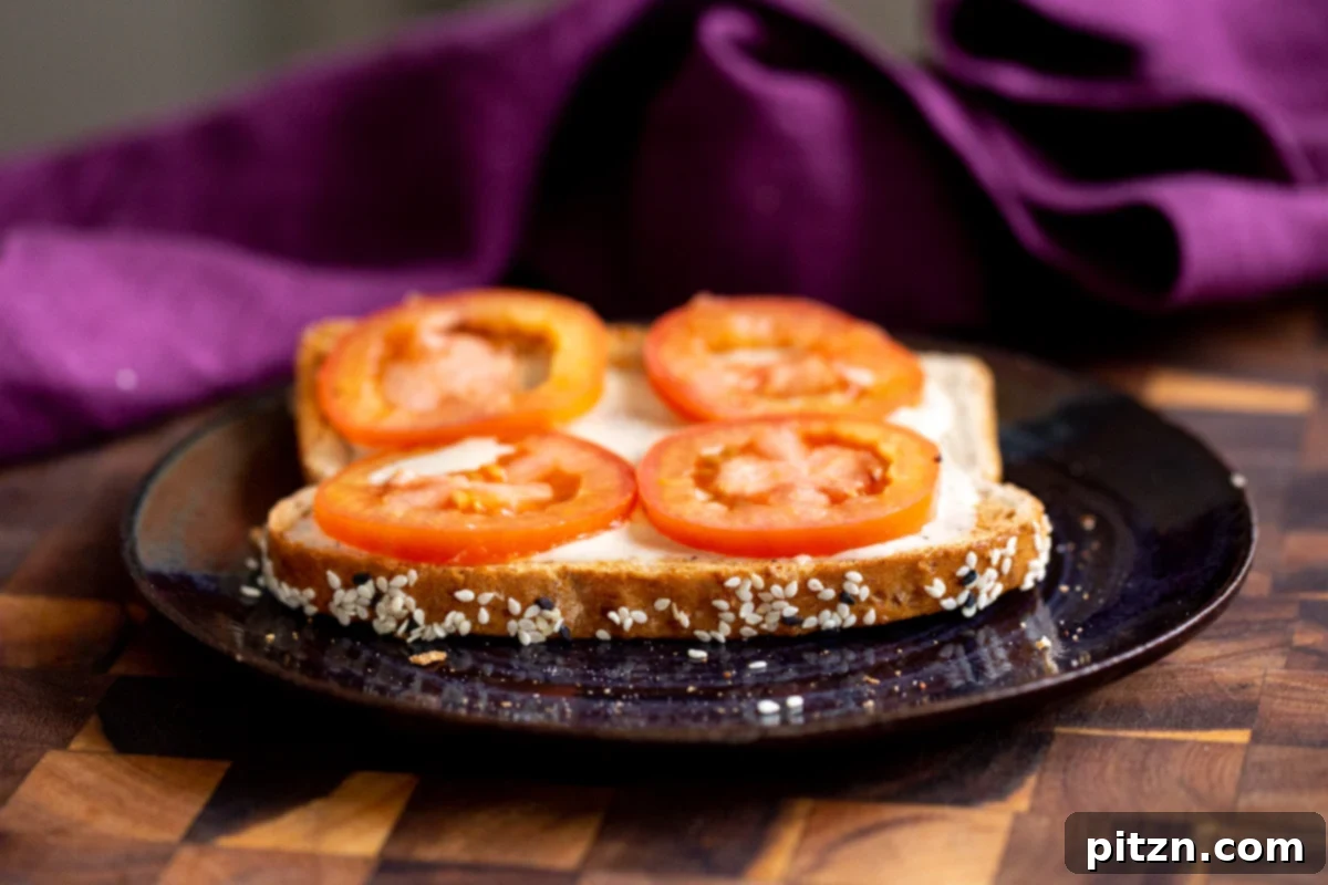 Savory Chickpea Flour Breakfast Combo 14 A slice of toasted bread being topped with vegan ranch and fresh tomatoes