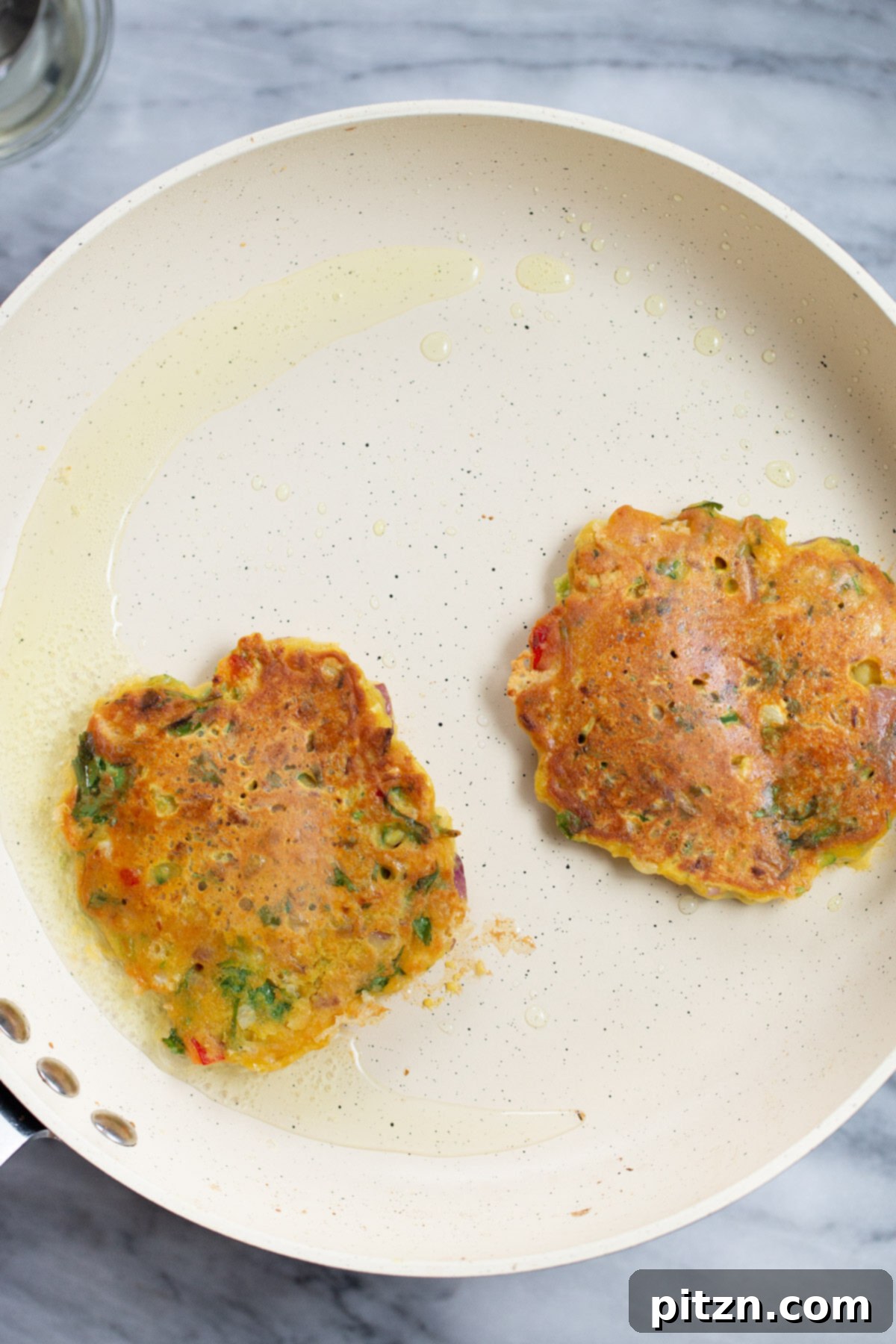 Savory Chickpea Flour Breakfast Combo 4 Crispy chickpea veggie pancakes cooking on a hot skillet