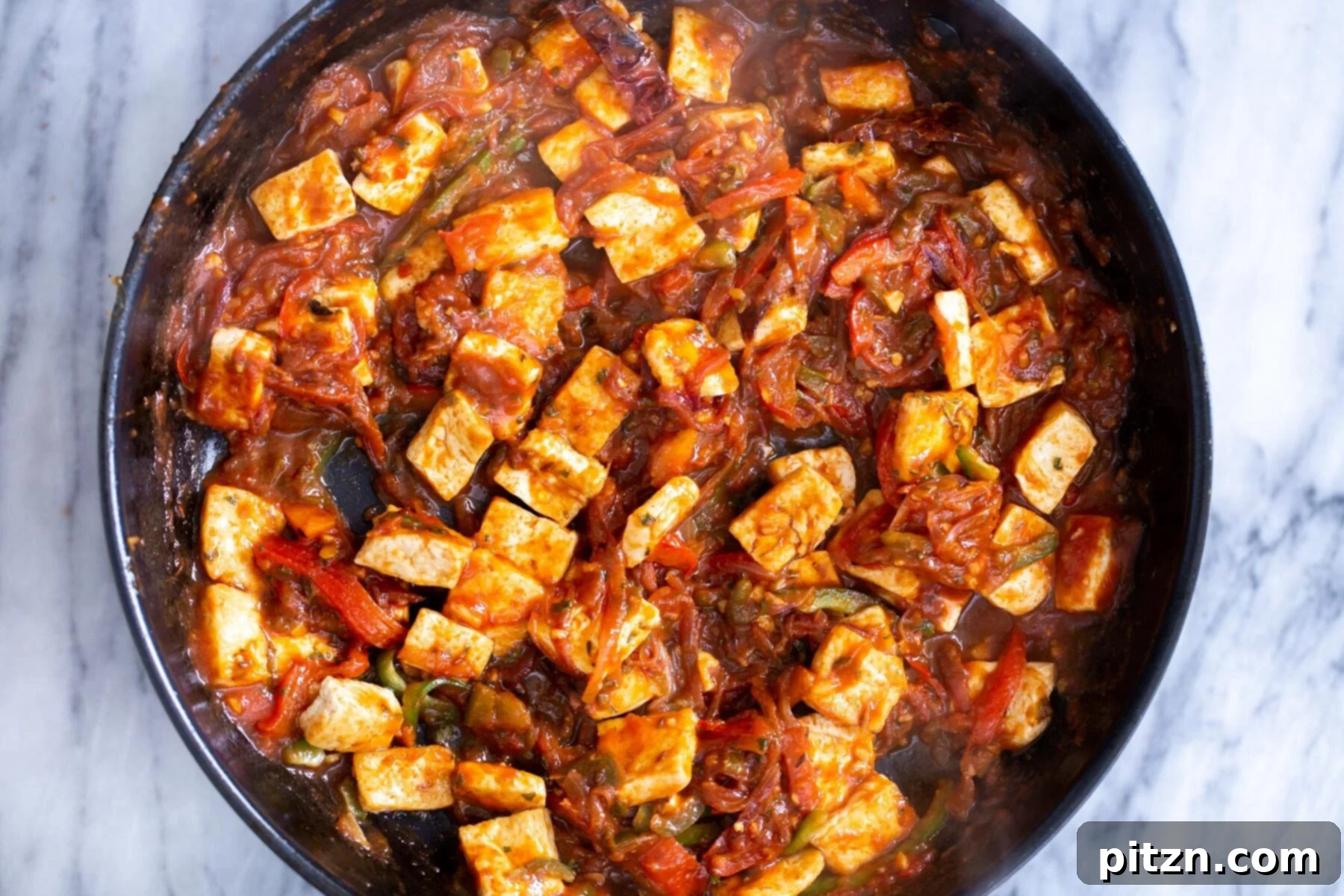 A finished Tofu Jalfrezi in a black skillet, vibrant with color and ready to be garnished and served.