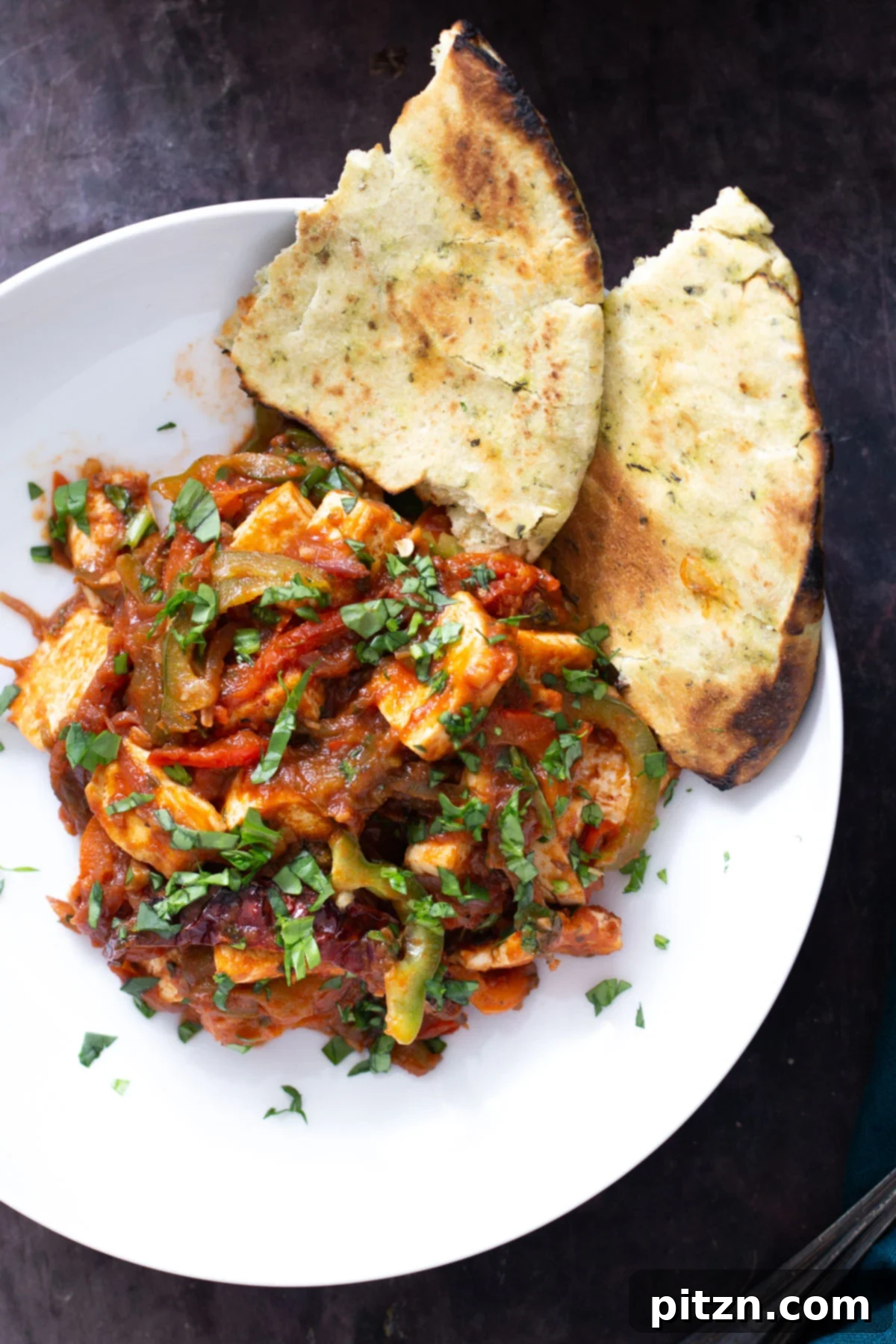 A beautiful serving of Vegan Tofu Jalfrezi curry, presented in a bowl with a generous side of warm naan bread, ready to be enjoyed.