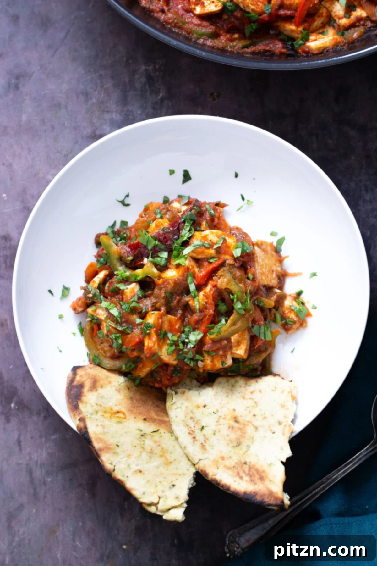 An overhead shot of a serving of Vegan Jalfrezi Tofu Curry beautifully plated with flatbread, inviting you to dig in.