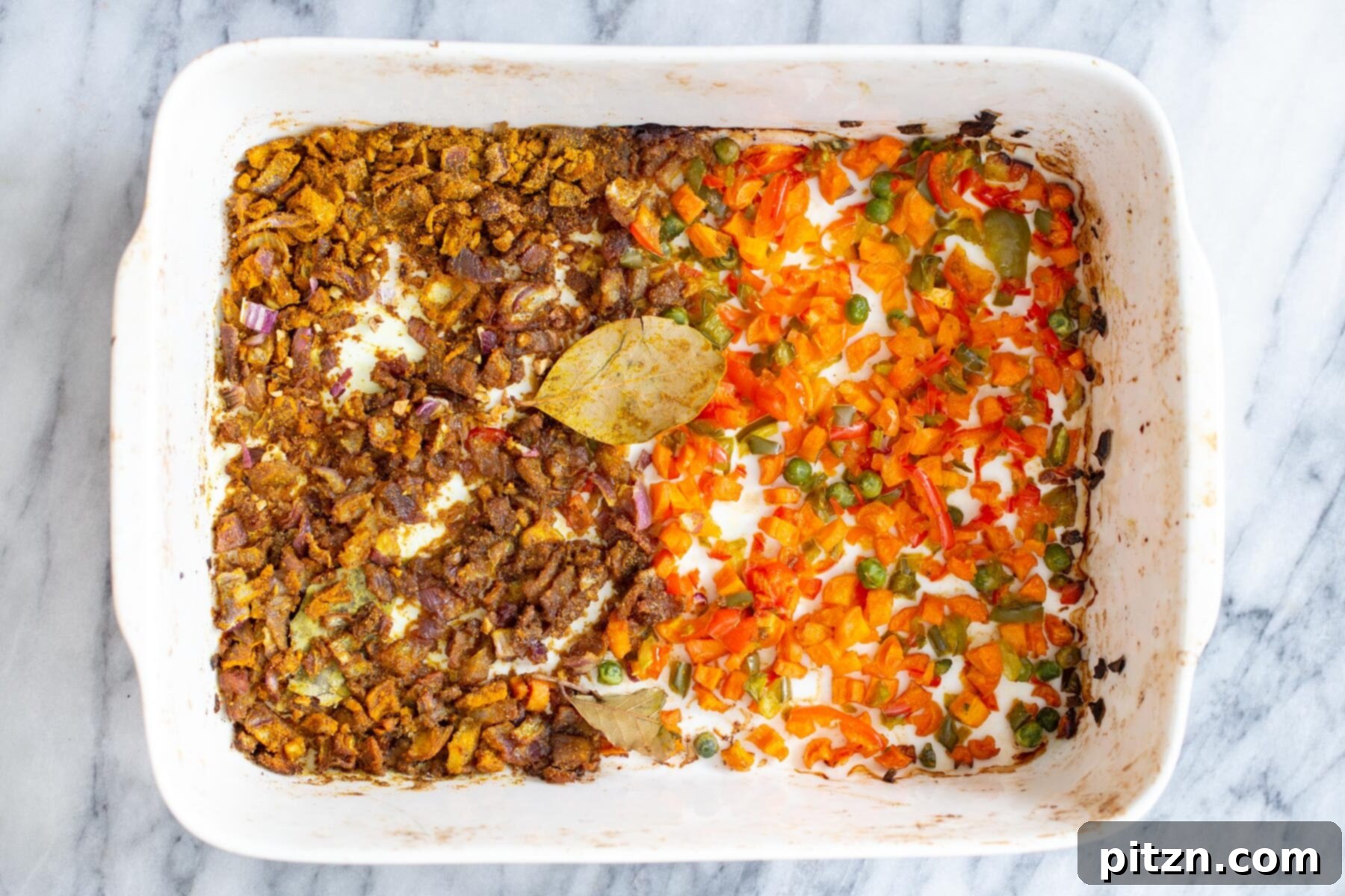 Golden Spiced Vegan Chickpea Rice Bake 9 Roasted spiced vegetables and golden onions in a white casserole dish, having developed deep flavors in the oven.