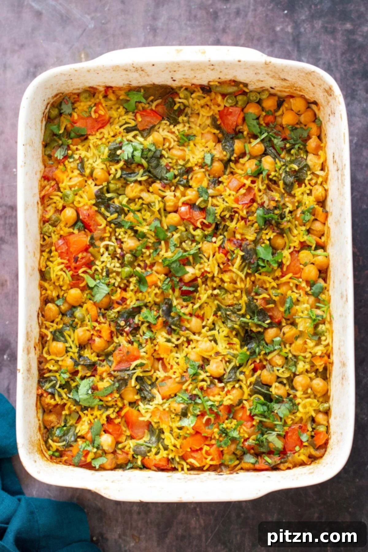 Golden Spiced Vegan Chickpea Rice Bake 2 A white casserole dish brimming with freshly baked vegan chickpea rice pulao, ready to be served.