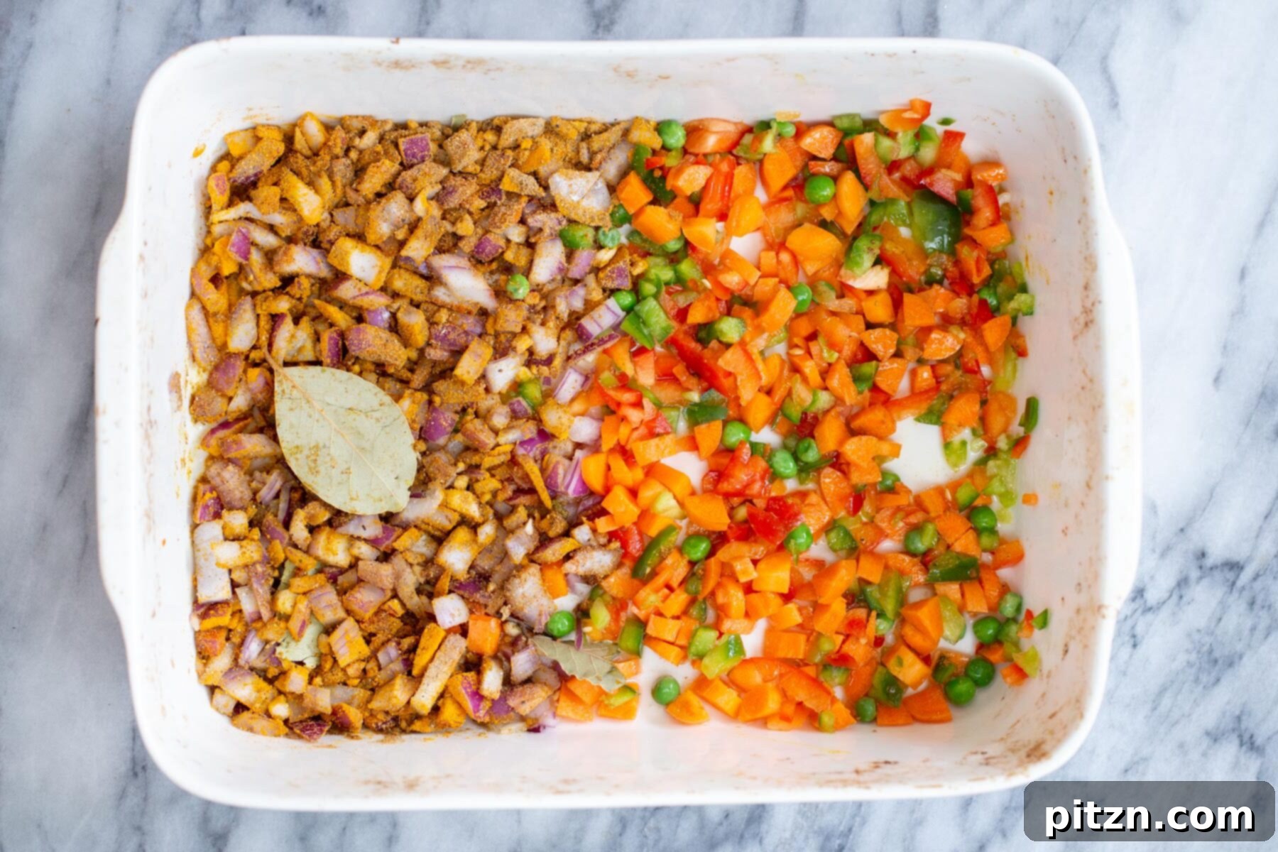 Golden Spiced Vegan Chickpea Rice Bake 8 Fresh vegetables arranged alongside spiced onions in a casserole dish, prepped for roasting.