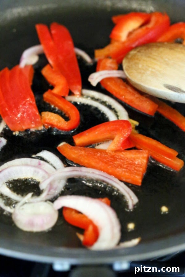 Red bell peppers and onions cooking in a hot skillet