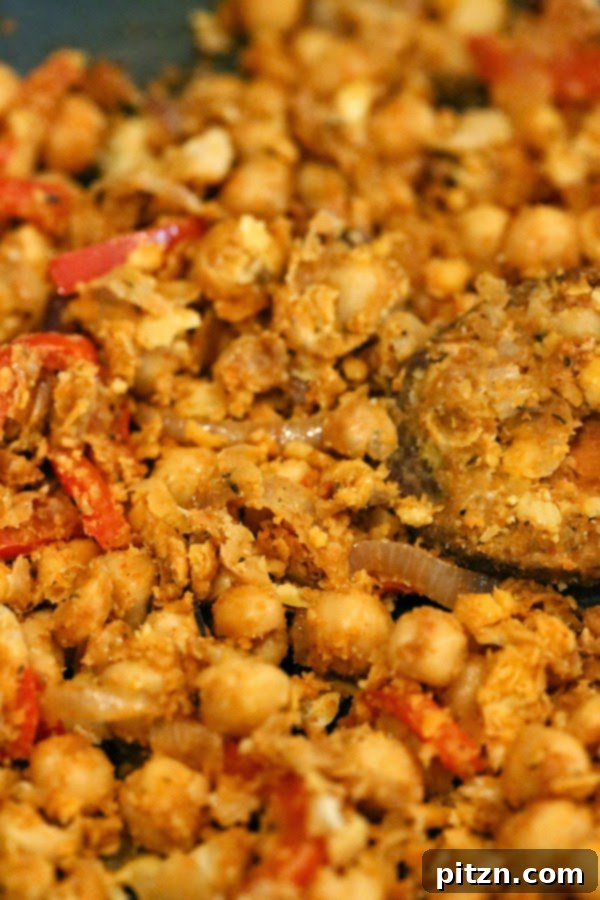 Mashed chickpeas sizzling in a skillet with spices and vegetables