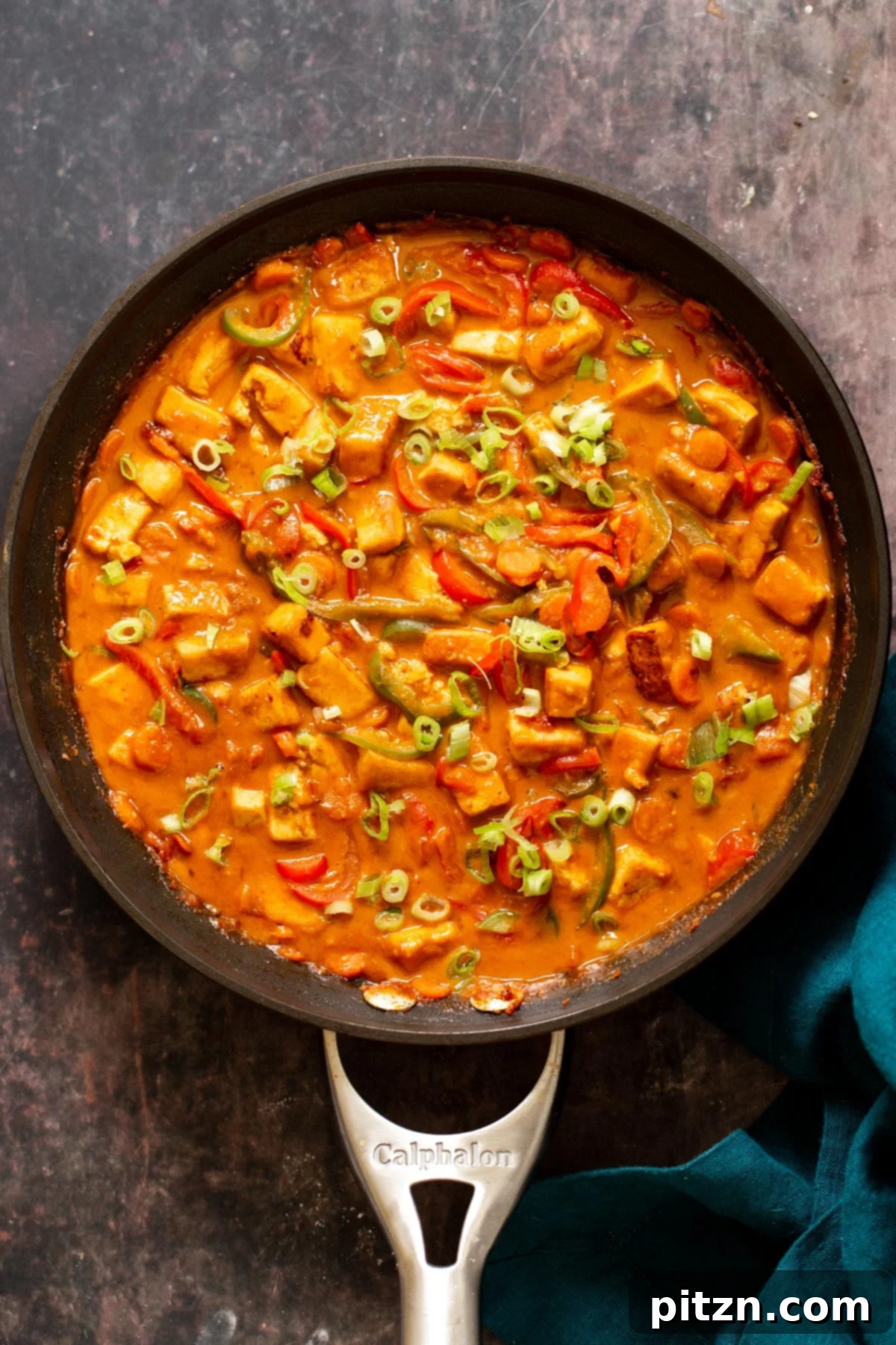 tofu and veggies in a skillet in creamy peanut butter sauce