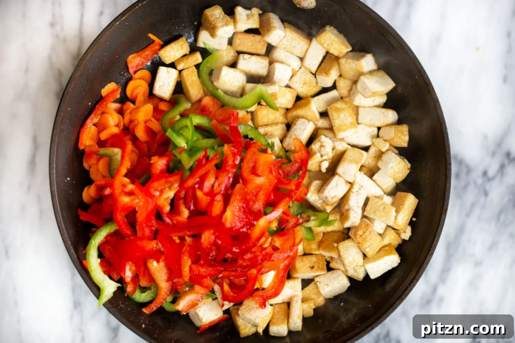 veggies and tofu cubes in a black skillet 
