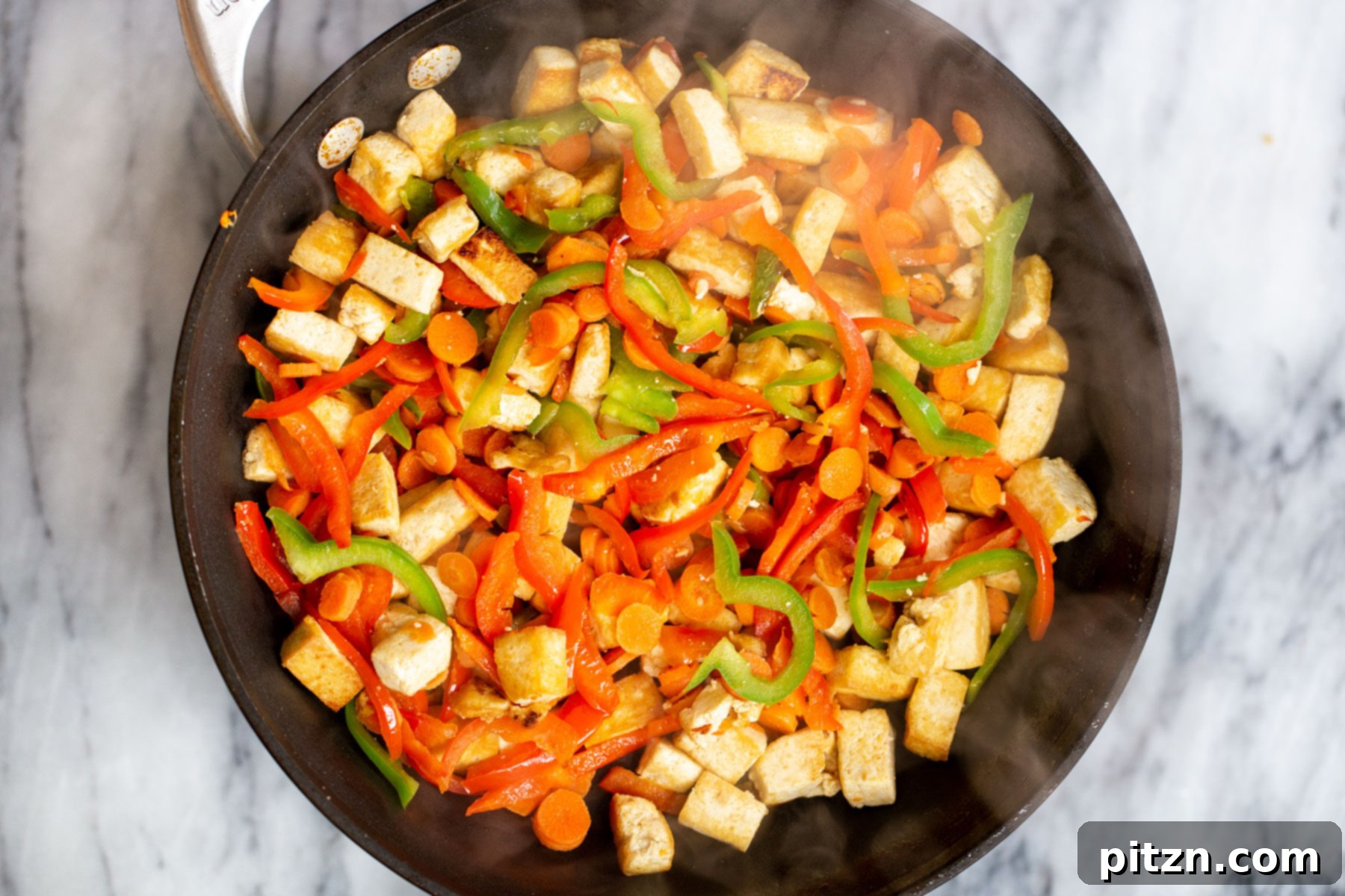 tofu cubes and bell peppers in a black skillet 