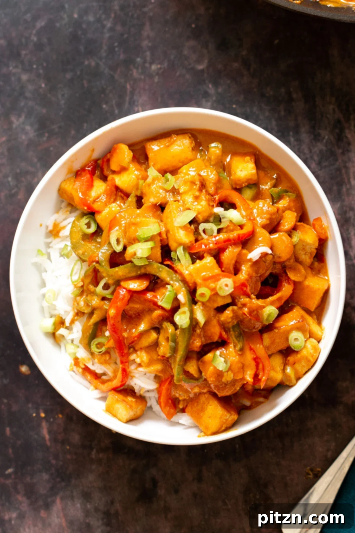 a bowl of gochujang tofu stir-fry served over rice in a white bowl 