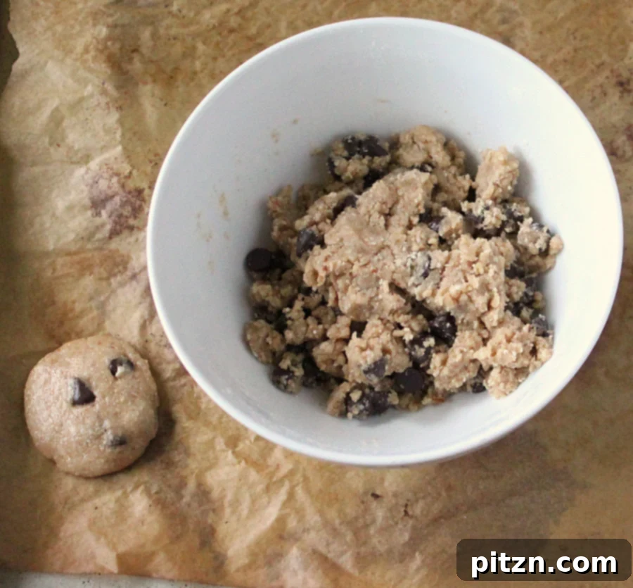 Unbaked cookie dough balls, flattened and ready to be placed in the oven, showing their rustic, handmade quality.