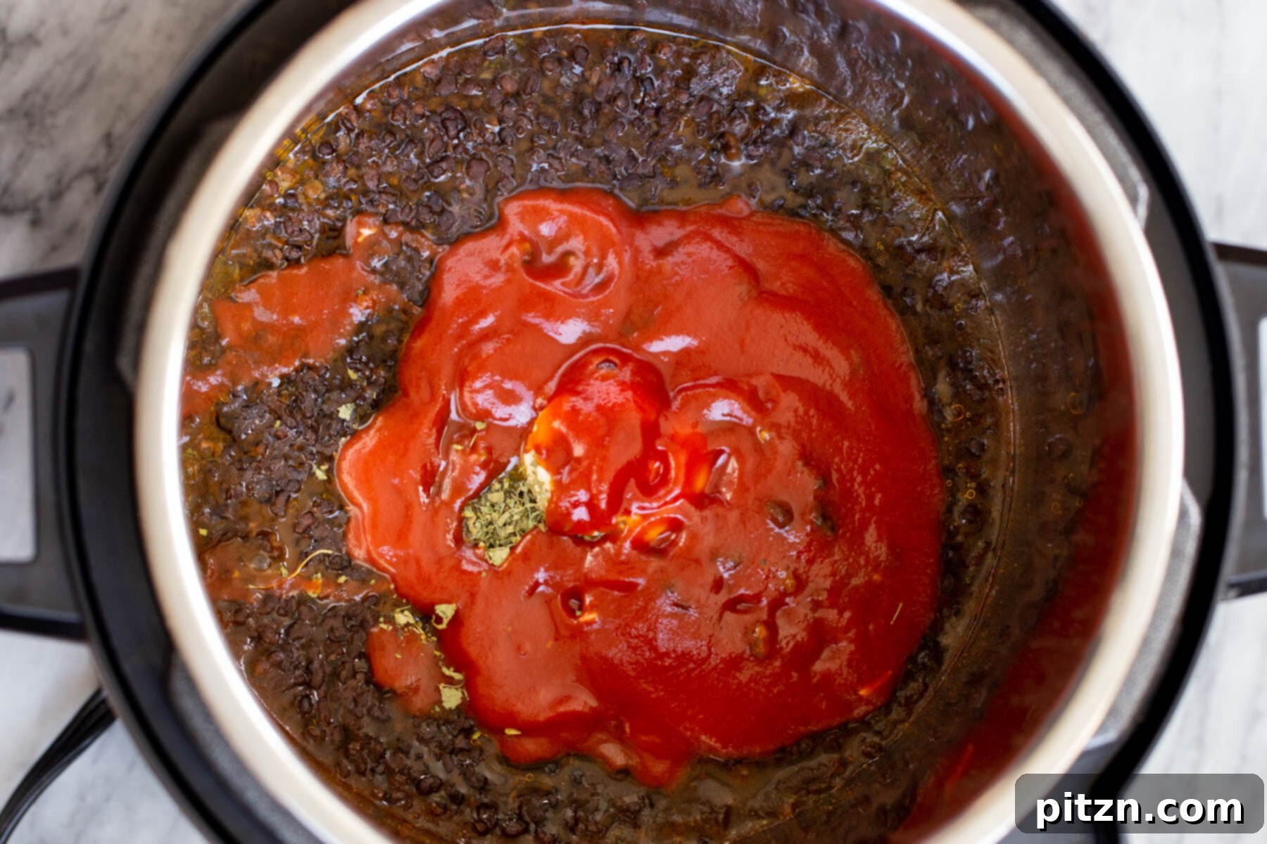 Instant Pot Dal Bukhara - Dump and Done Creamy Black Lentil Perfection 12 Rich tomato puree being stirred into a pot of perfectly cooked black gram lentils within an Instant Pot, enhancing flavor and color.