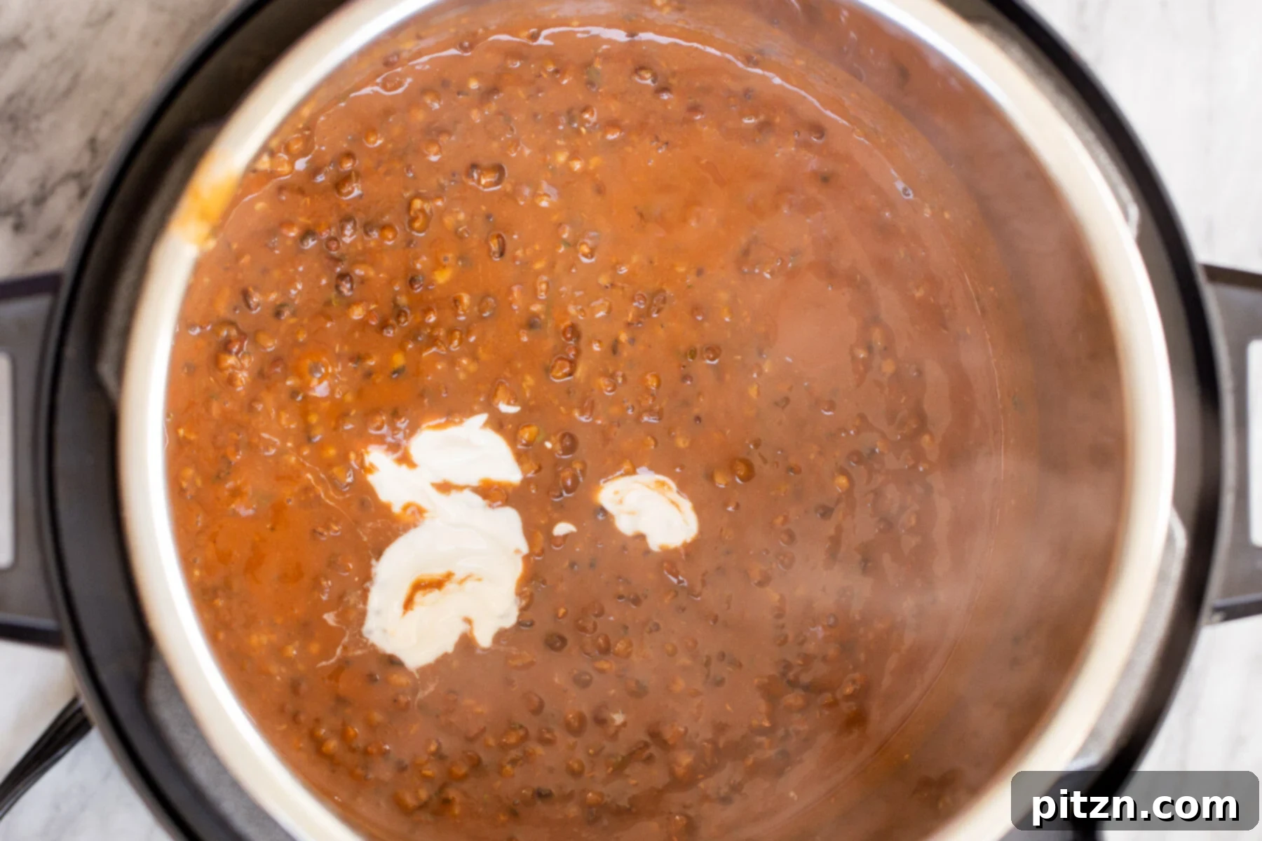 Instant Pot Dal Bukhara - Dump and Done Creamy Black Lentil Perfection 13 Creamy cashew cream being gently poured into an Instant Pot filled with delicious Instant Pot Dal Bukhara, adding richness.