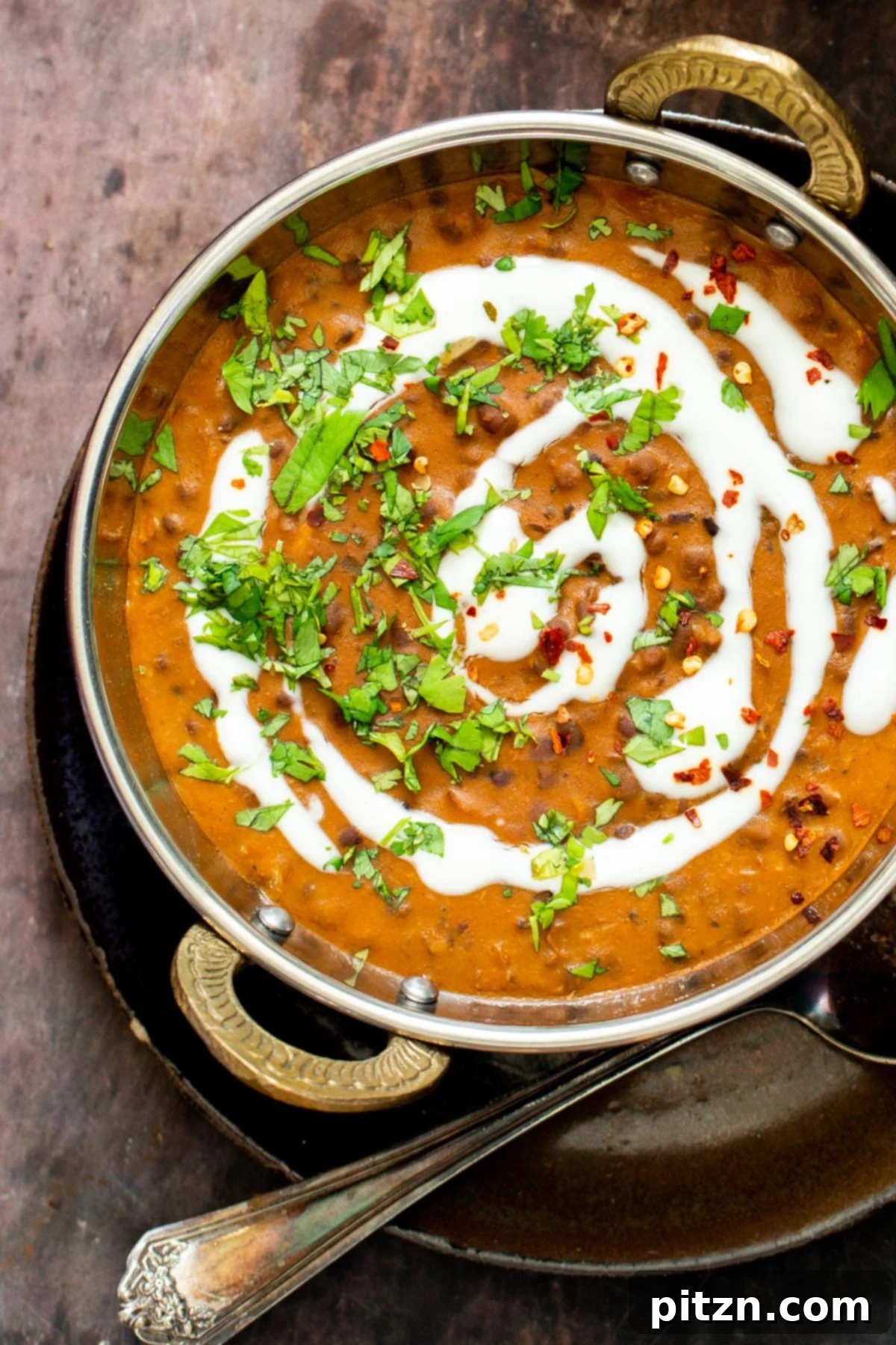 Instant Pot Dal Bukhara - Dump and Done Creamy Black Lentil Perfection 5 A platter of creamy Dal Bukhara, elegantly drizzled with vegan cream and fresh cilantro, alongside a sprinkle of pepper.