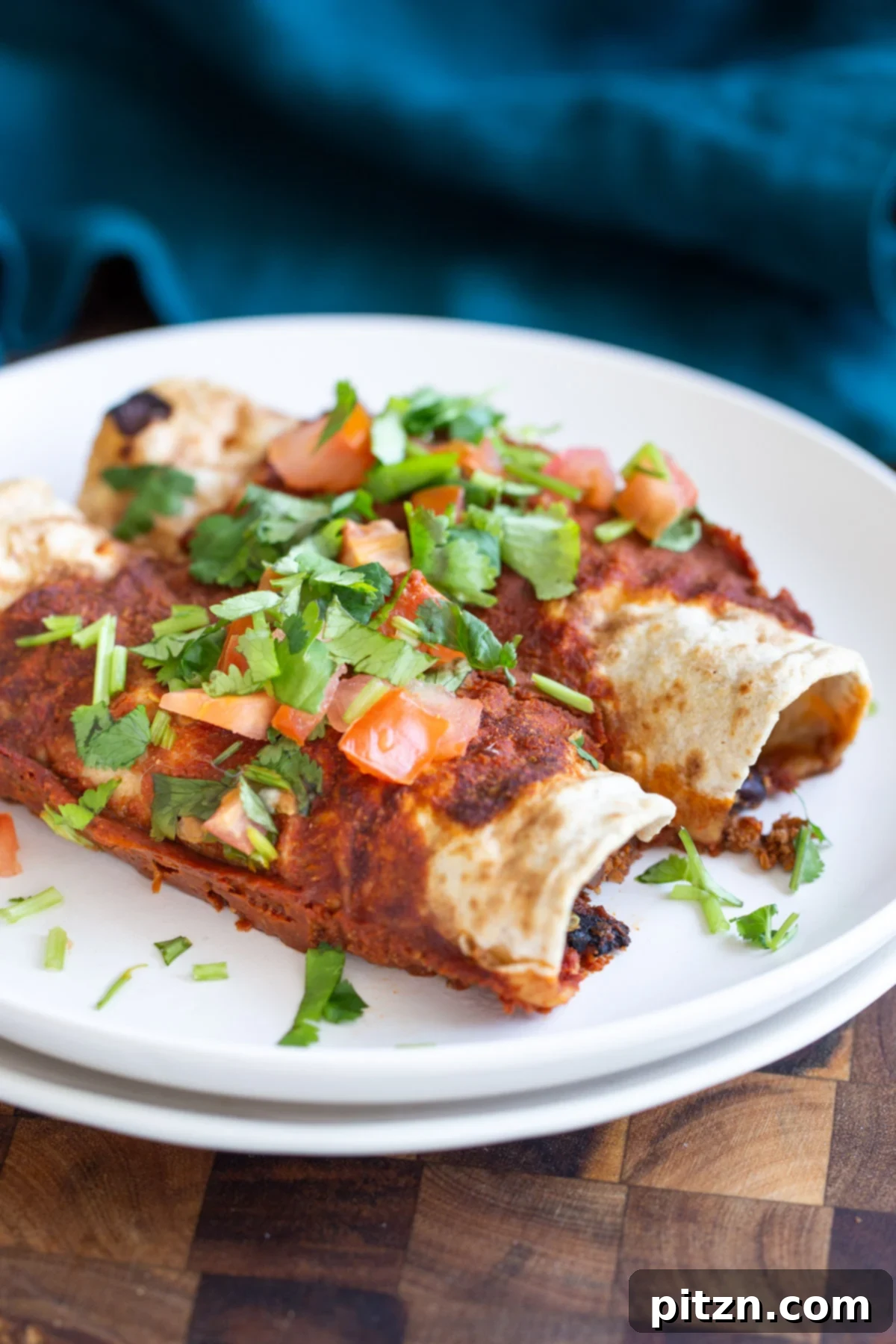 Delicious vegan enchiladas filled with cauliflower taco meat served on white plates, garnished with fresh herbs.