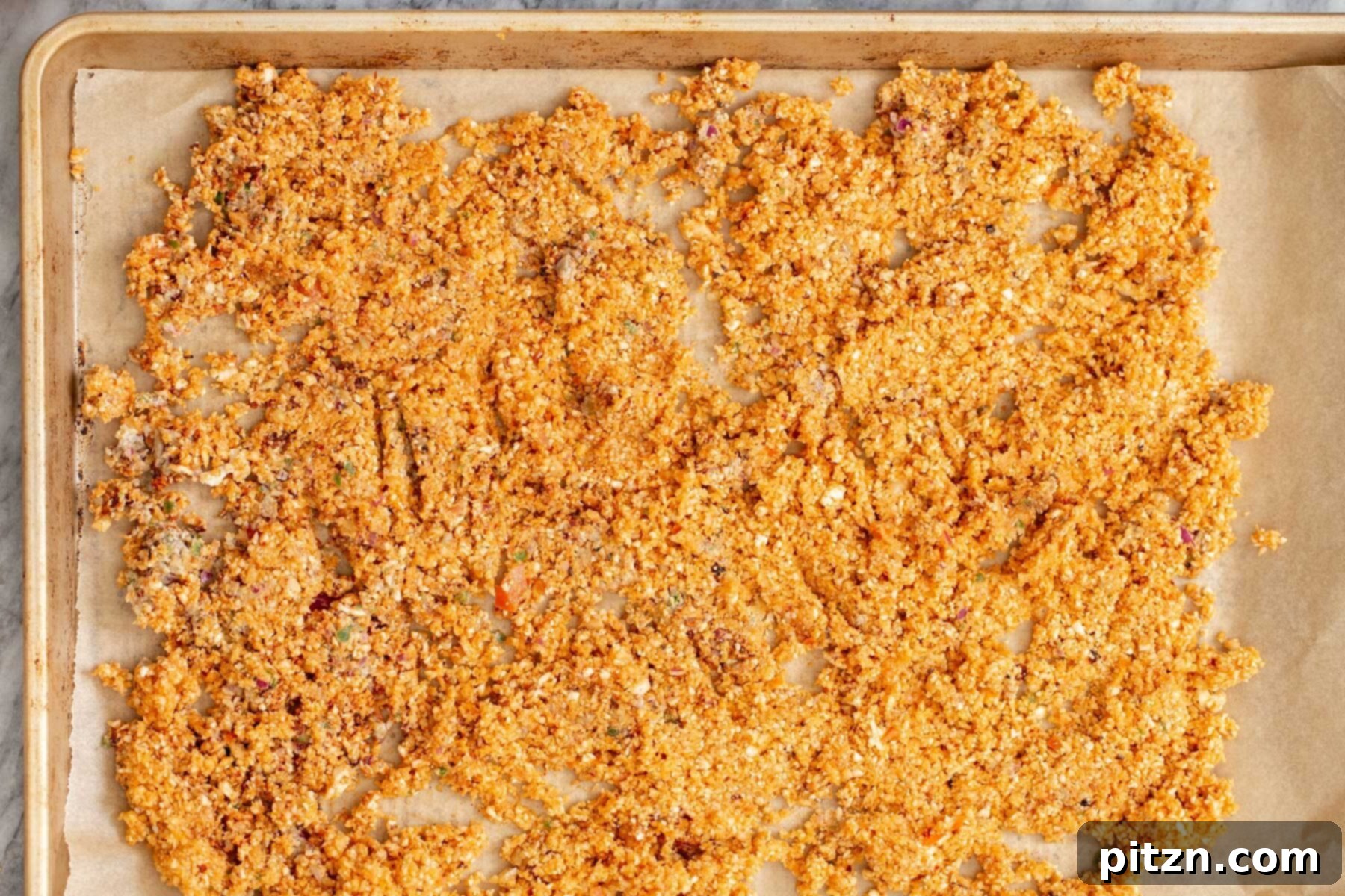 Roasted cauliflower taco meat spread evenly on a parchment-lined baking sheet, showing a golden brown color.