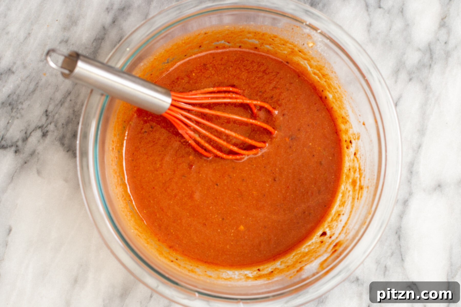 A fresh batch of vibrant red vegan enchilada sauce in a bowl, ready to be used.